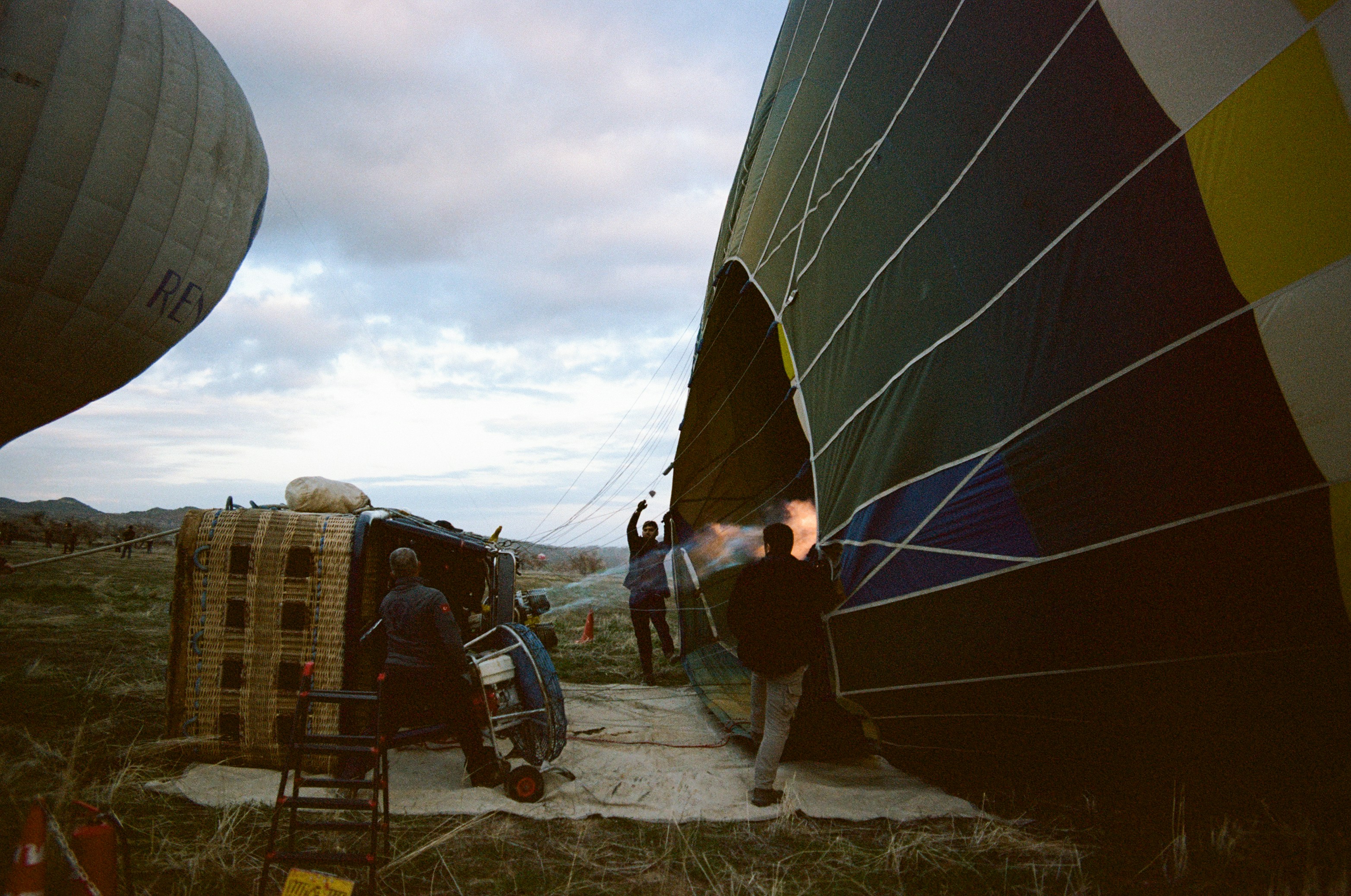 People inflating a large hot air balloon on a field at low sun