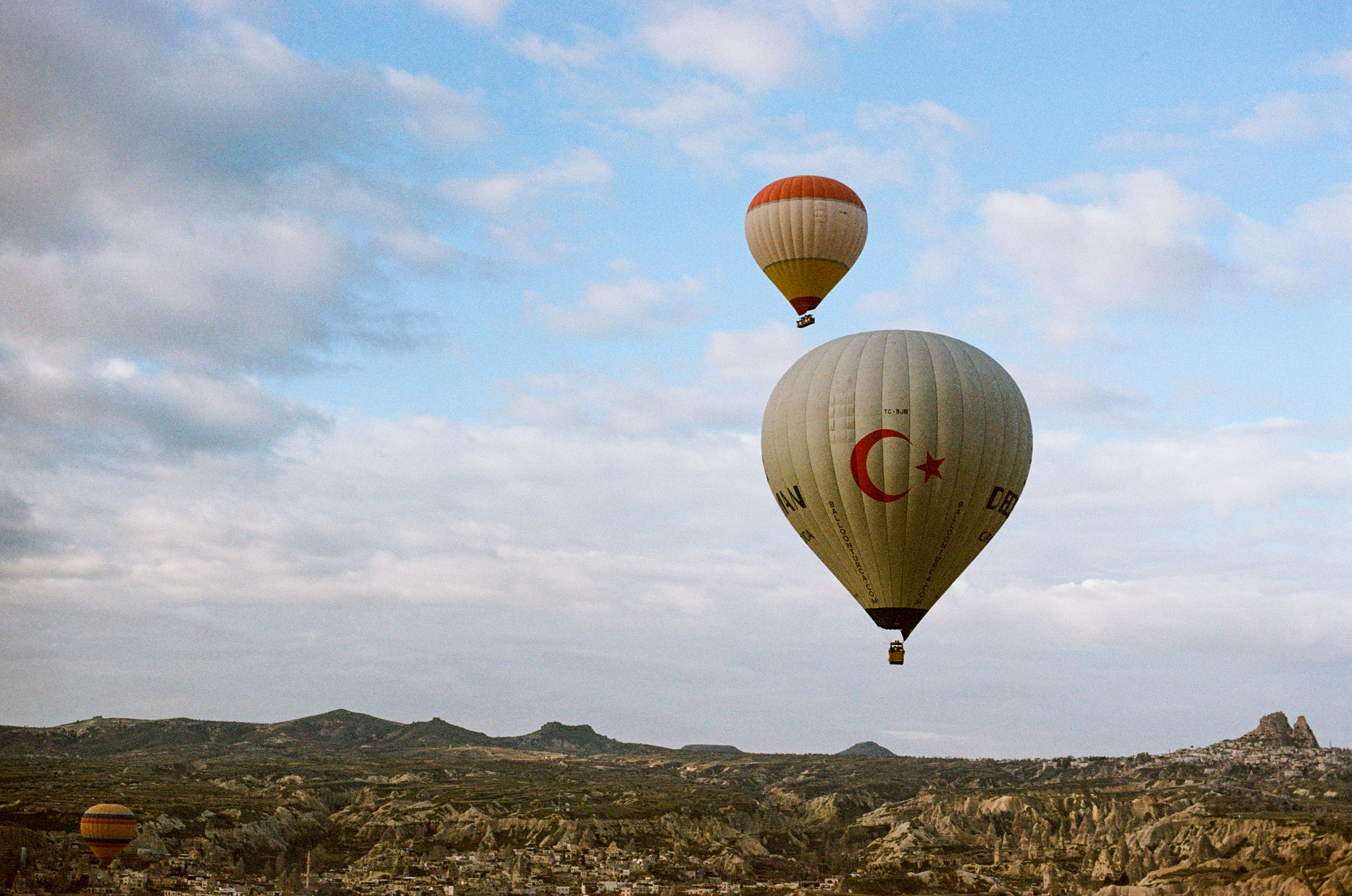 Three hot air balloons floating over the rocky landscape of Cappadocia in Turkey