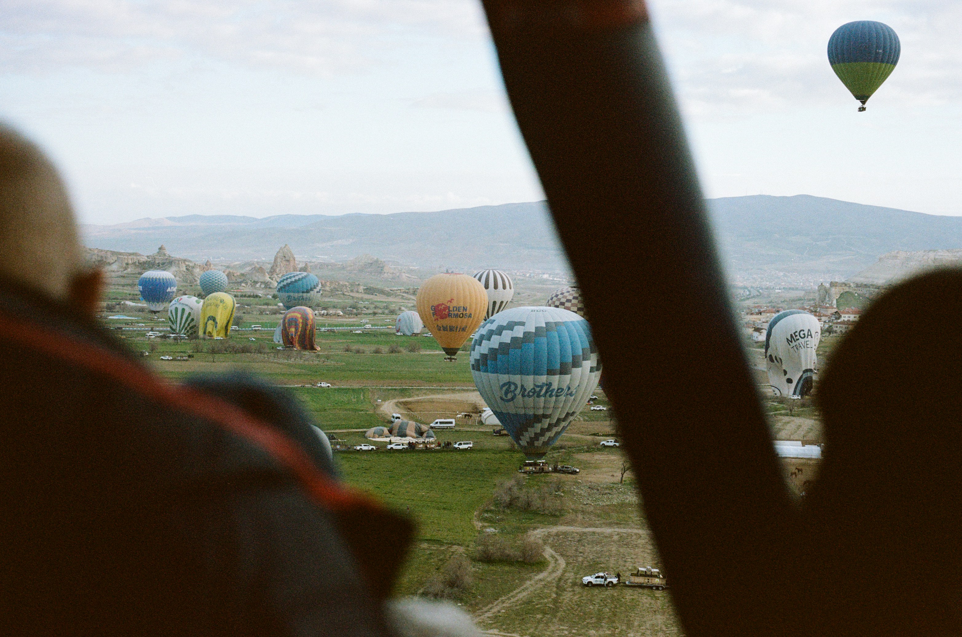 Many hot air balloons floating over a green valley in Cappadocia, Turkey