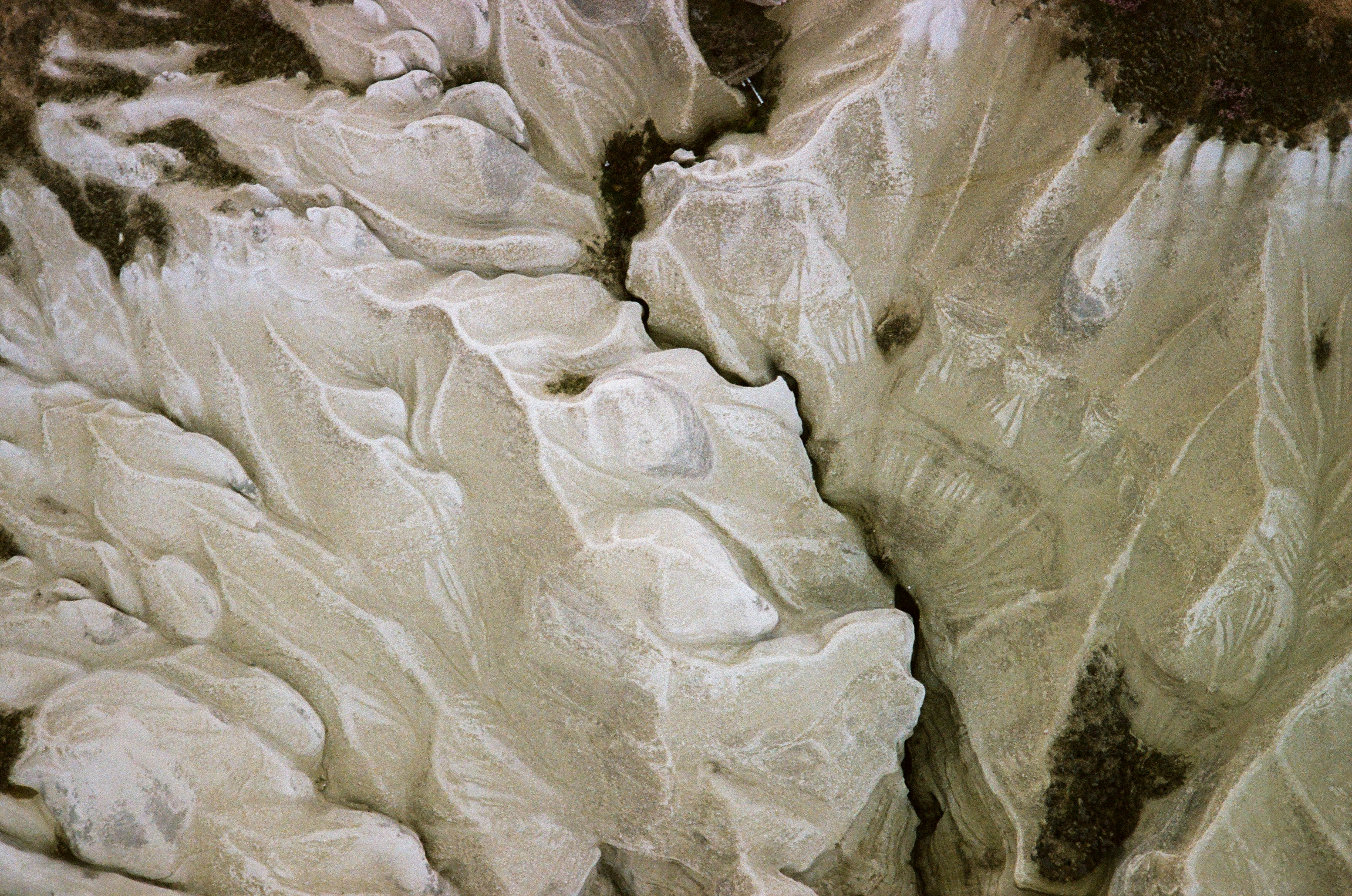 An aerial view of eroded light beige sandstone formations with deep crevices