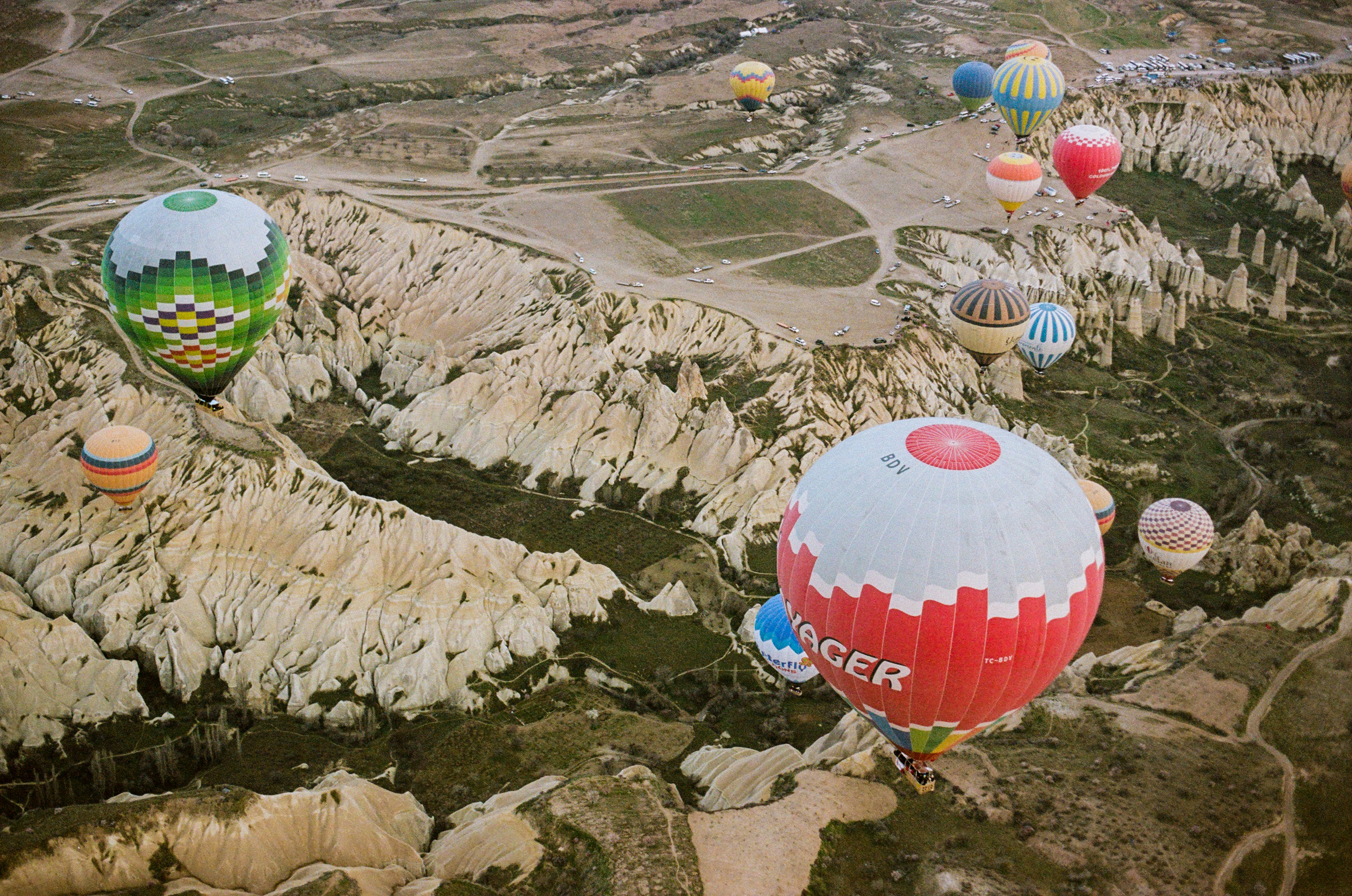 Many colorful hot air balloons floating over the rocky landscape of Cappadocia, Turkey