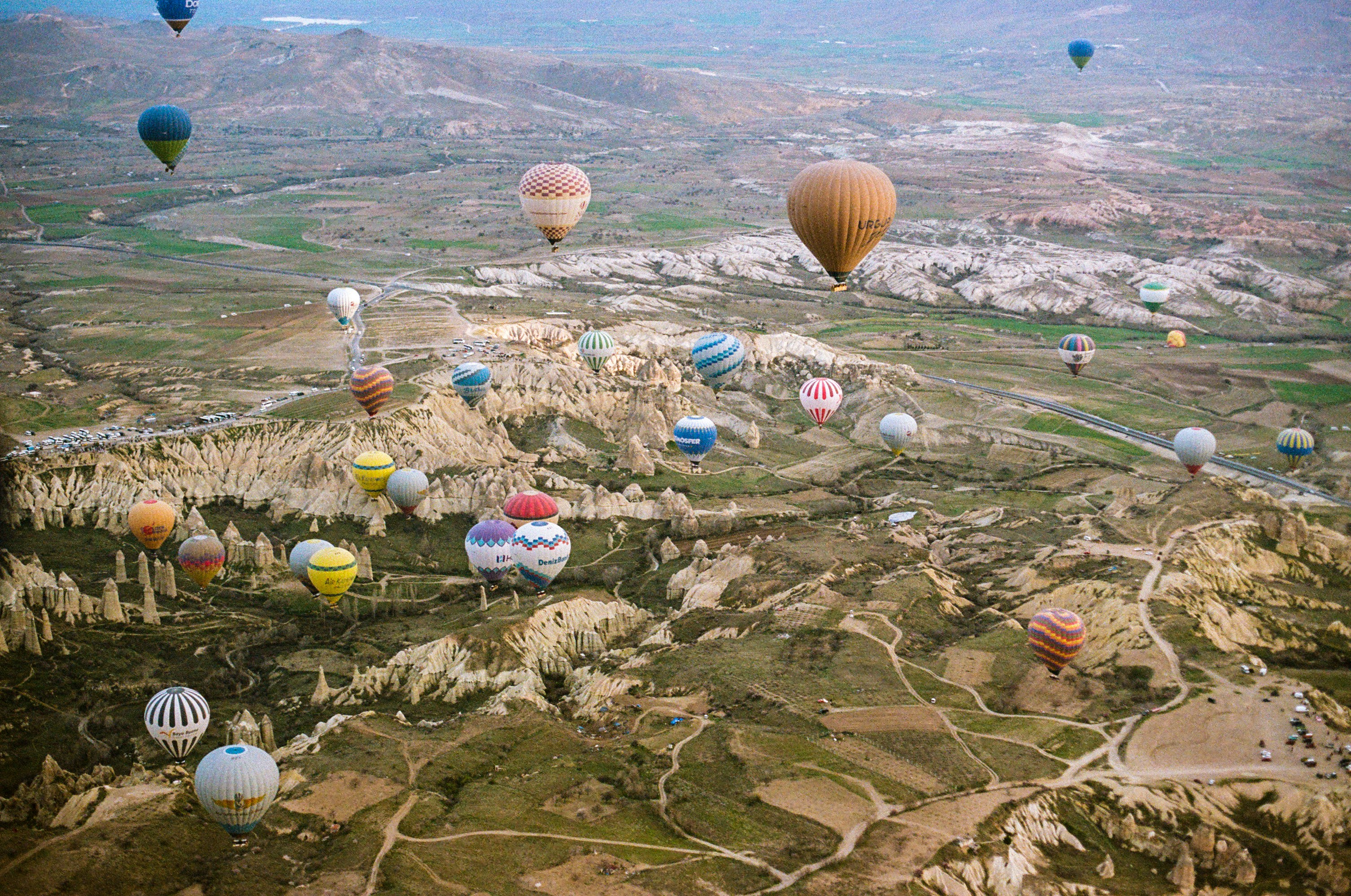 Many colorful hot air balloons floating over the rocky landscape of Cappadocia, Turkey