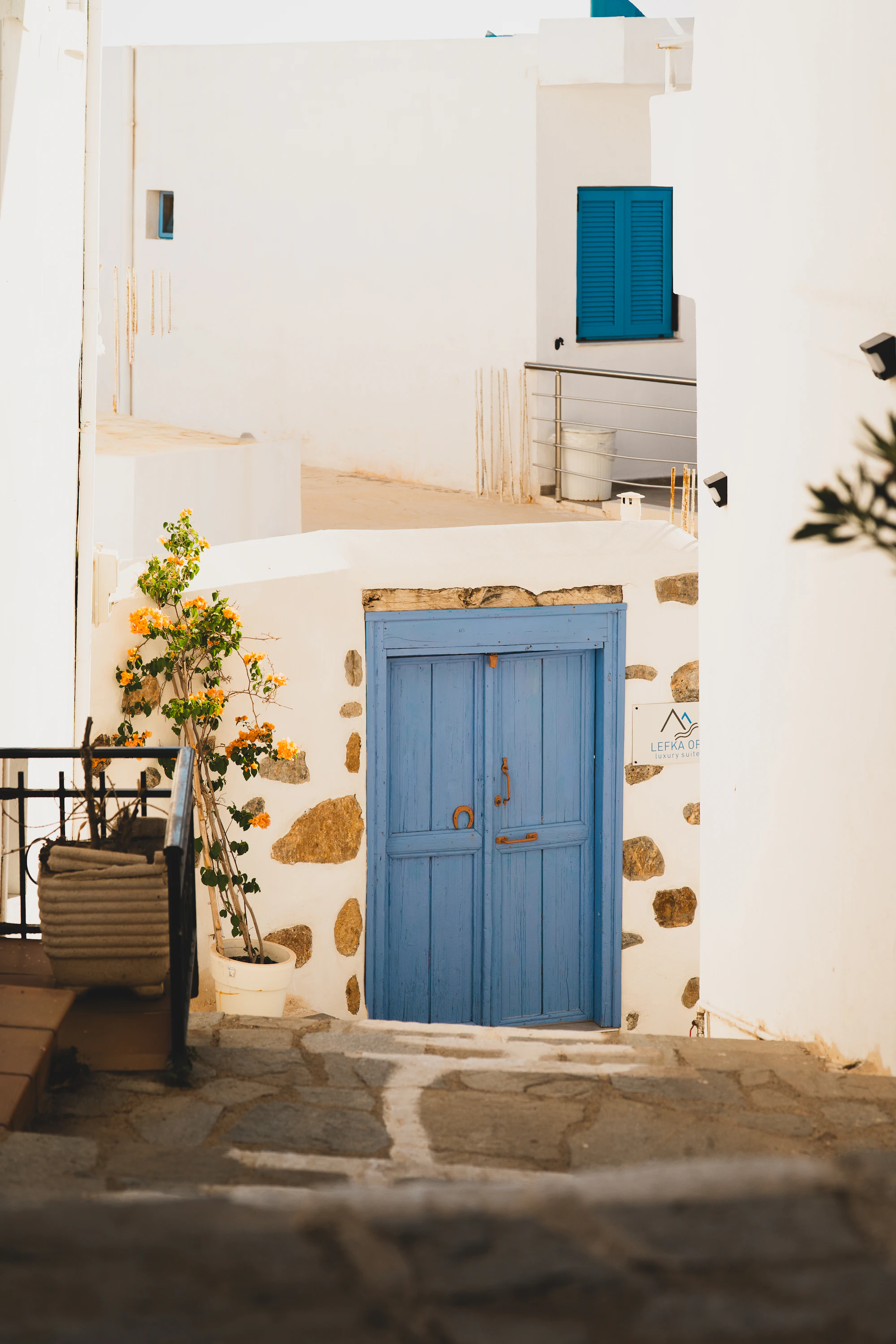 A blue door in a white stone wall with bougainvillea