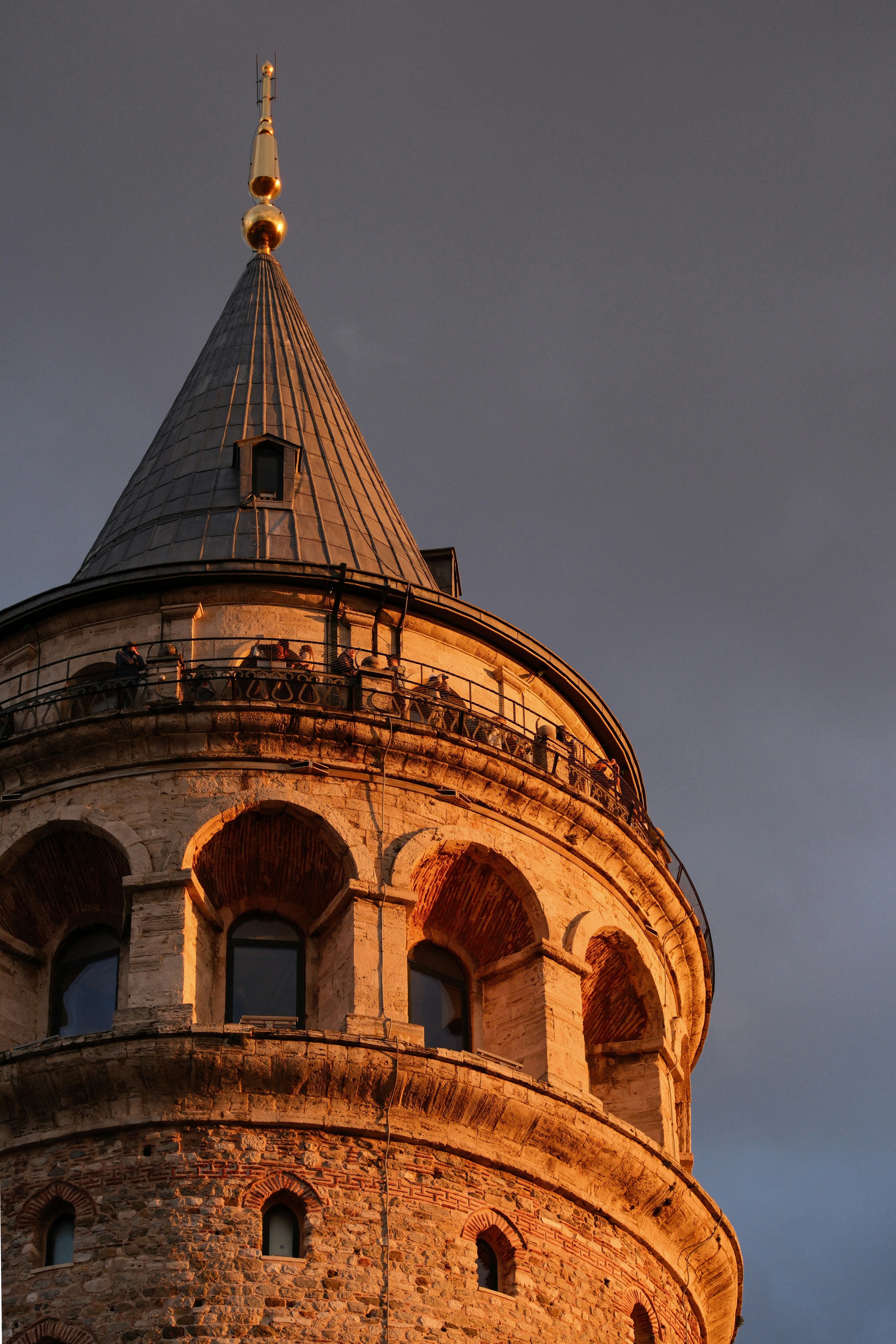 The Galata Tower in Istanbul with people on the observation deck at golden hour
