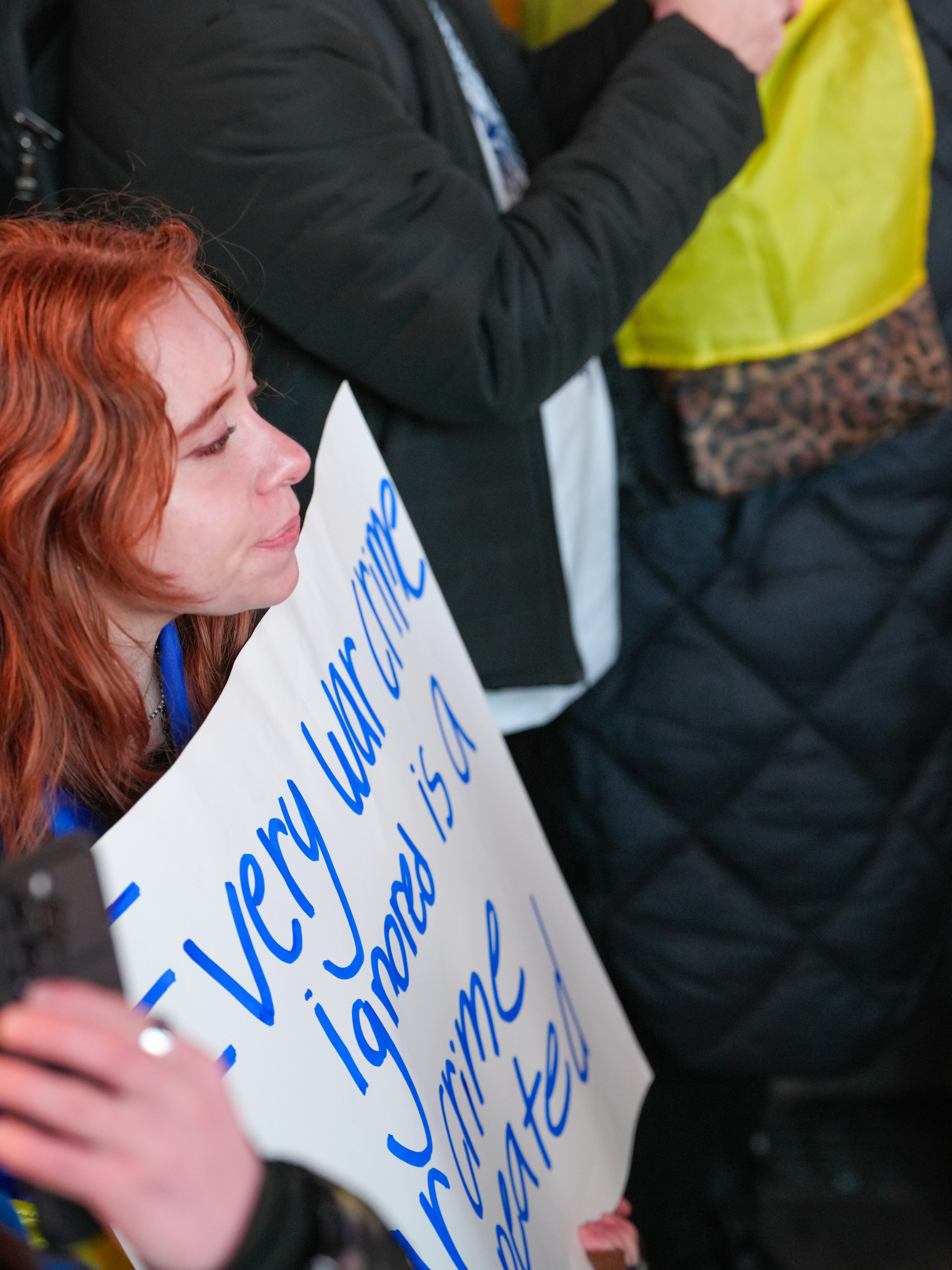 A person with red hair holding a sign with blue handwritten text