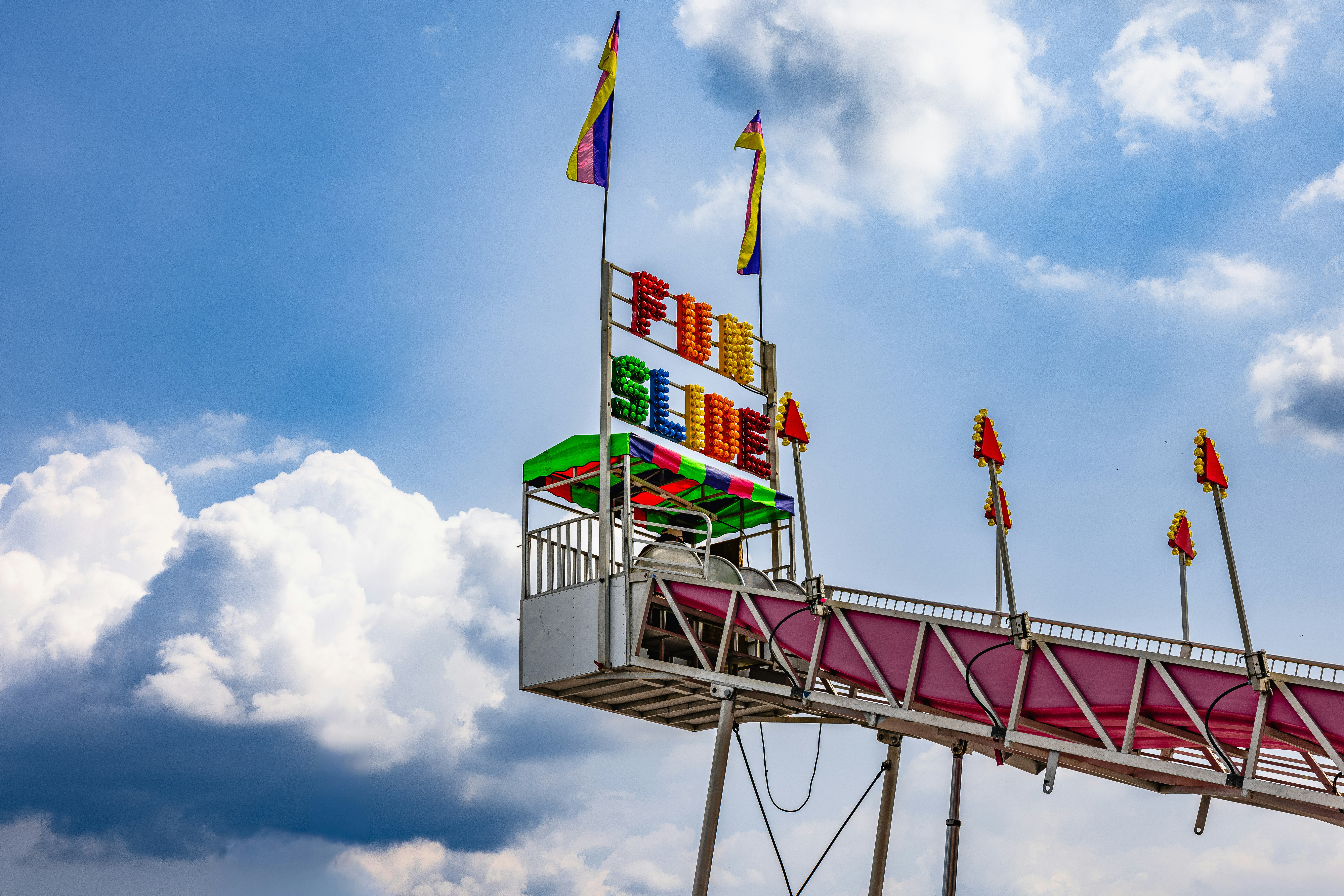 A carnival fun slide with colorful lettering against a bright blue sky