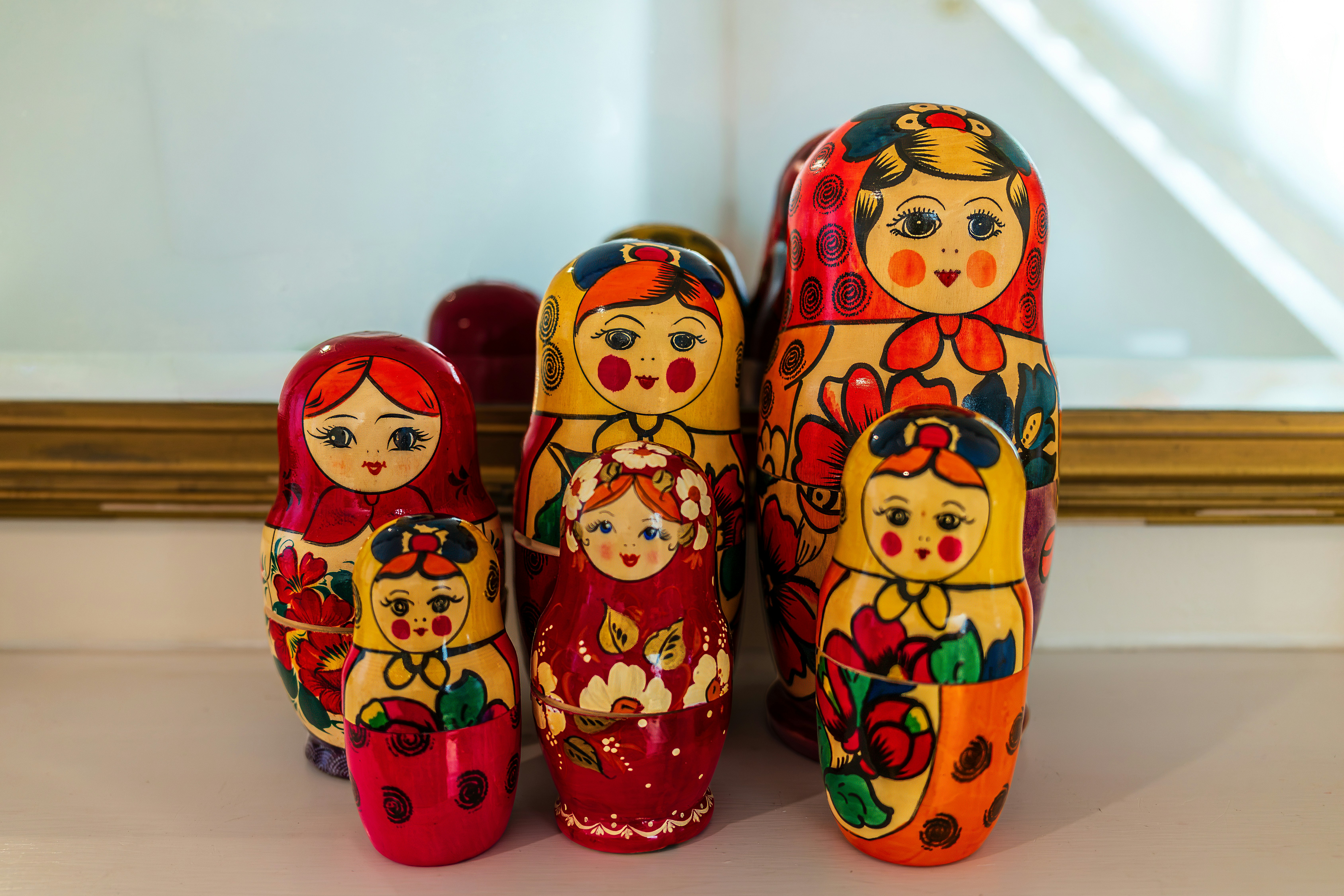 A group of five colorful wooden matryoshka dolls on a white surface