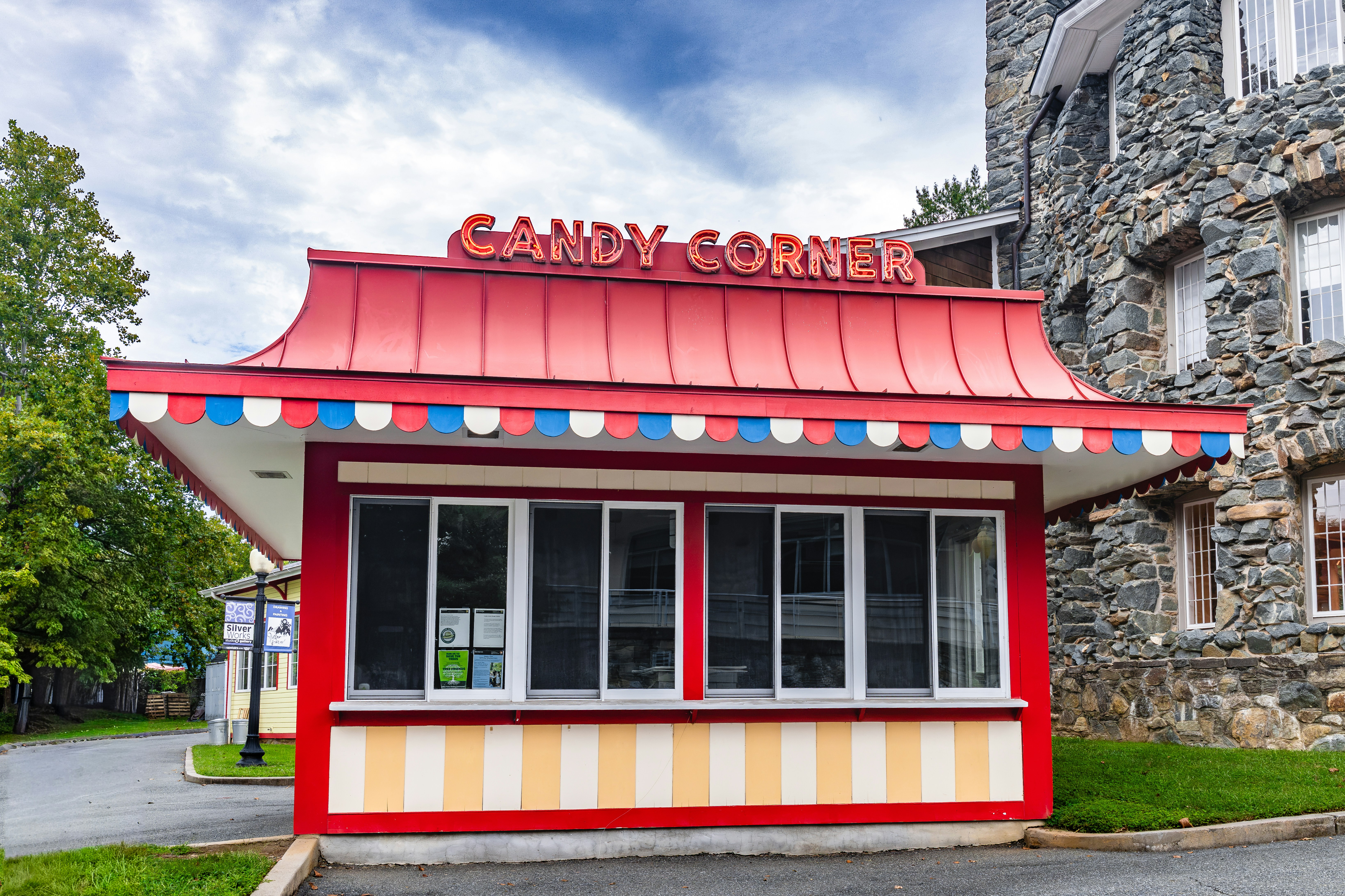 A red and white candy stand with a sign reading CANDY CORNER