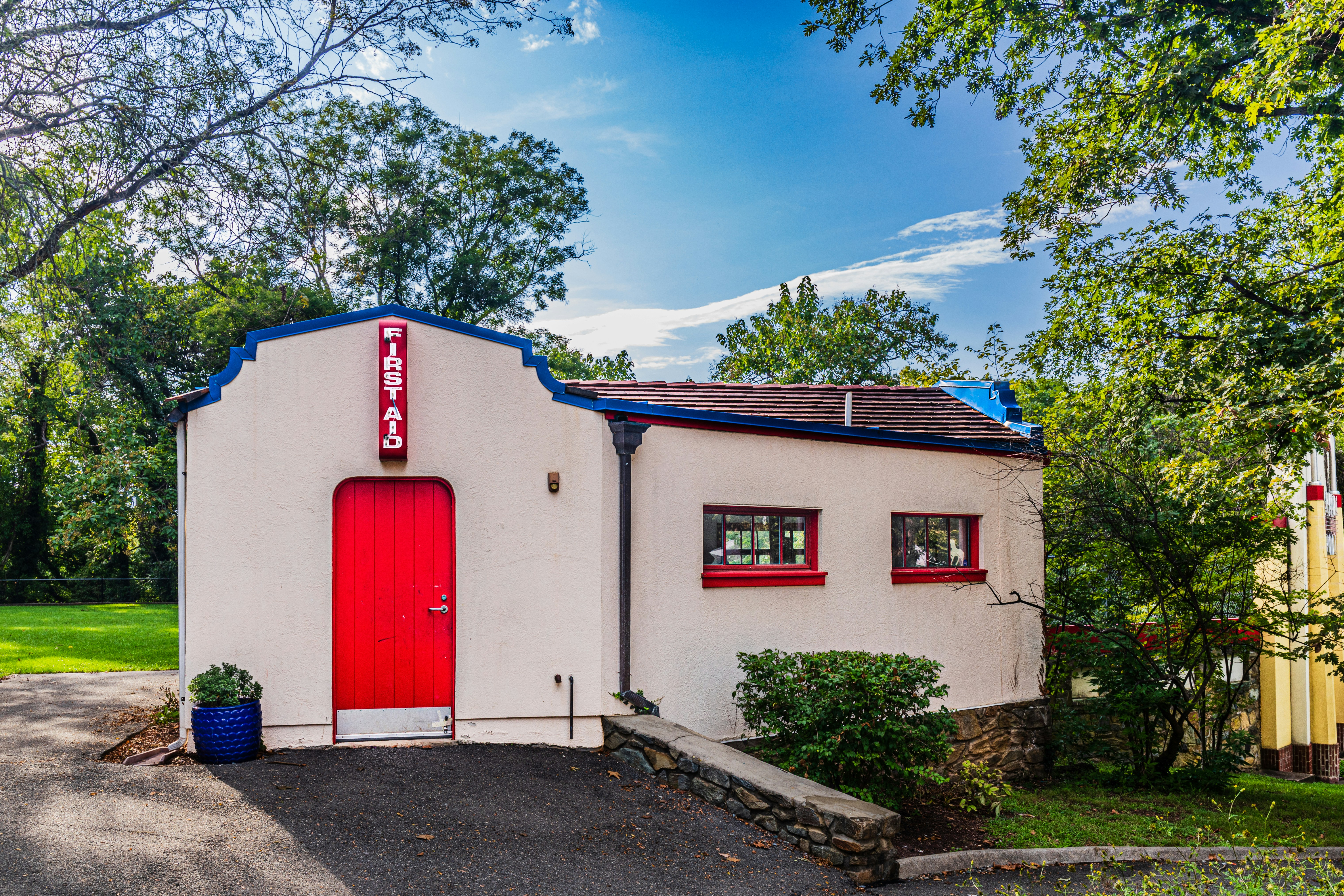 A small building with a red door and a sign reading FIRST AID