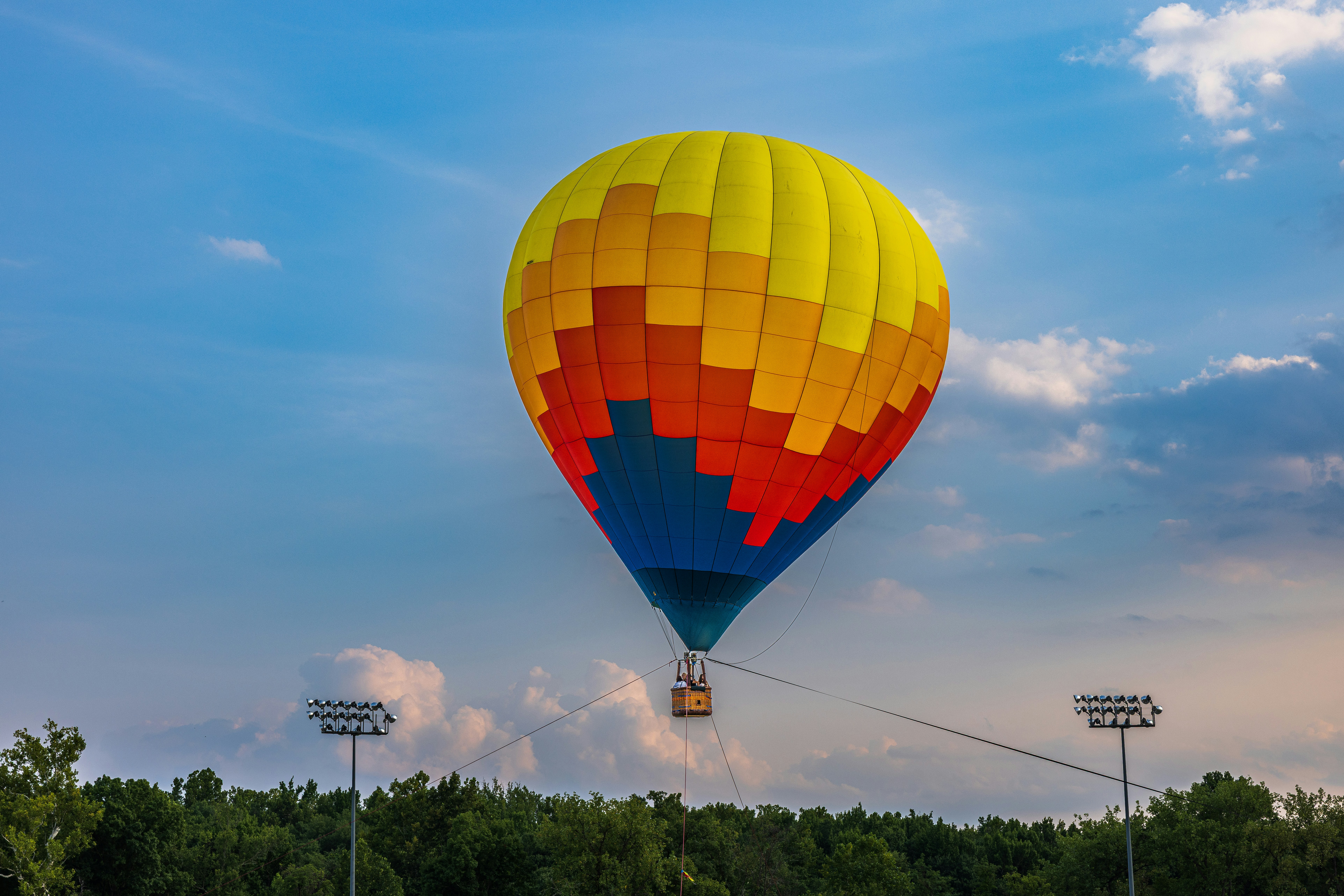 Ein bunter Heißluftballon, der über einem Wald unter blauem Himmel schwebt
