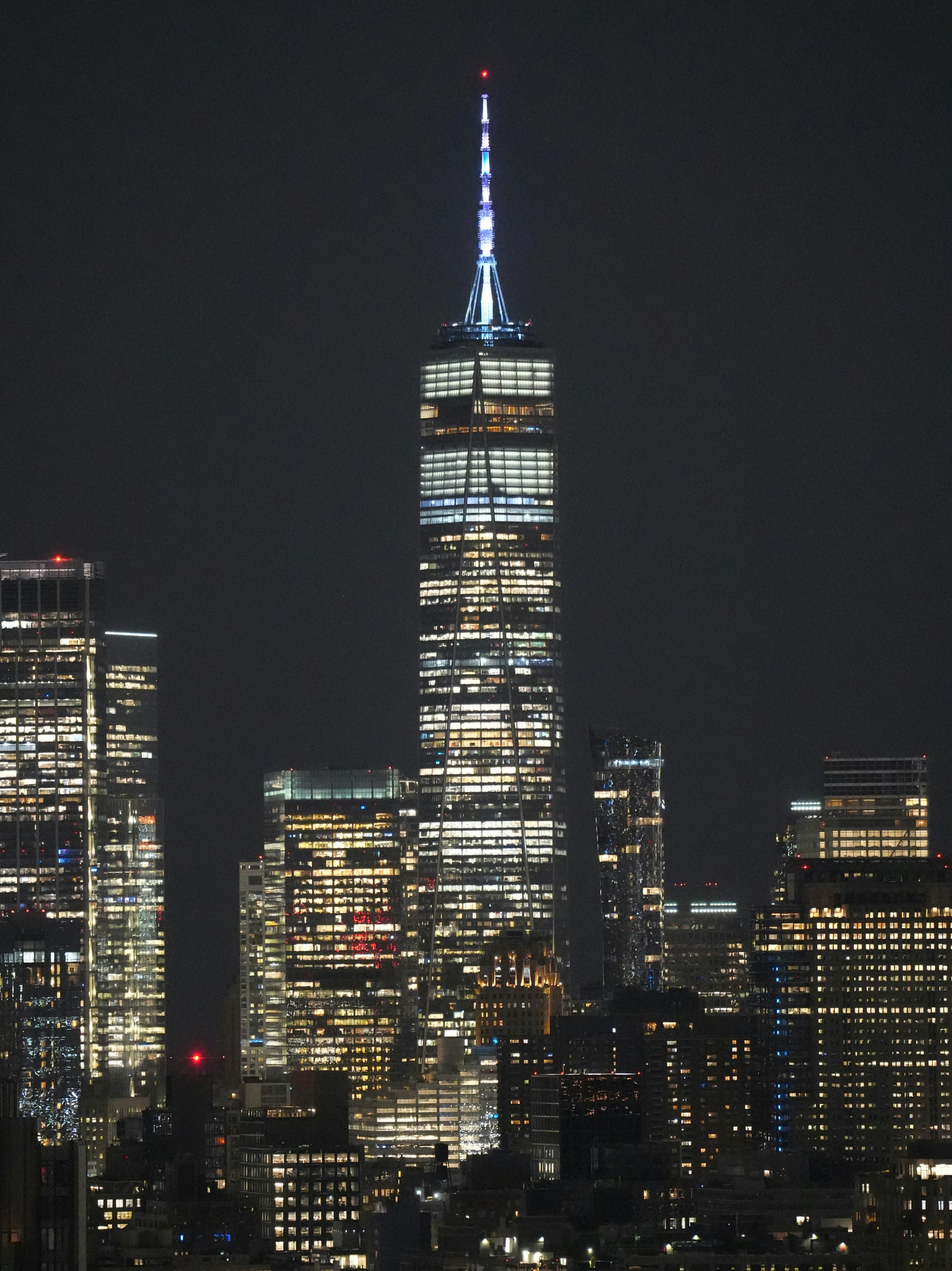 One World Trade Center illuminated at night among the skyscrapers of New York City