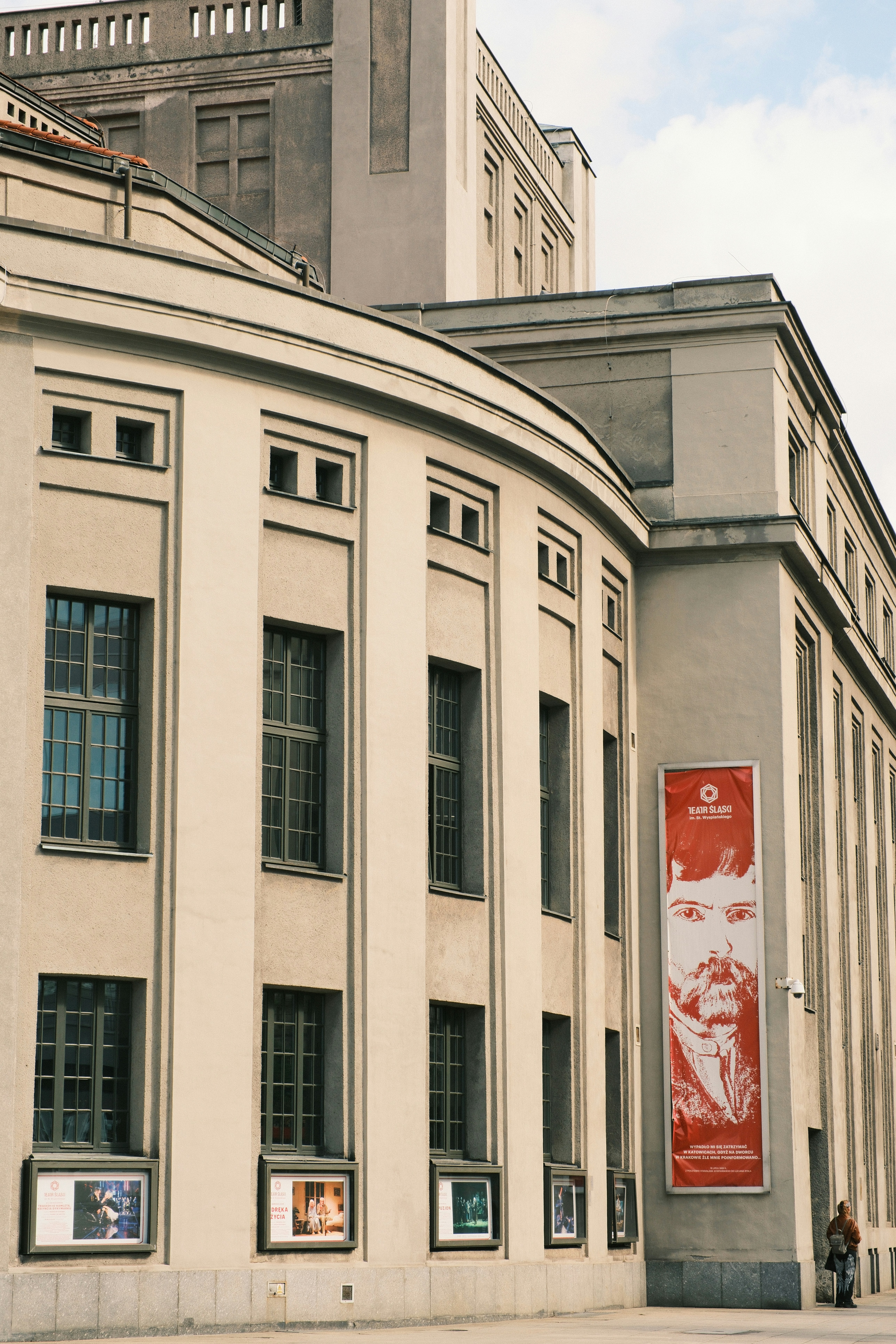 The curved facade of the Silesian Theatre in Katowice with a large red banner
