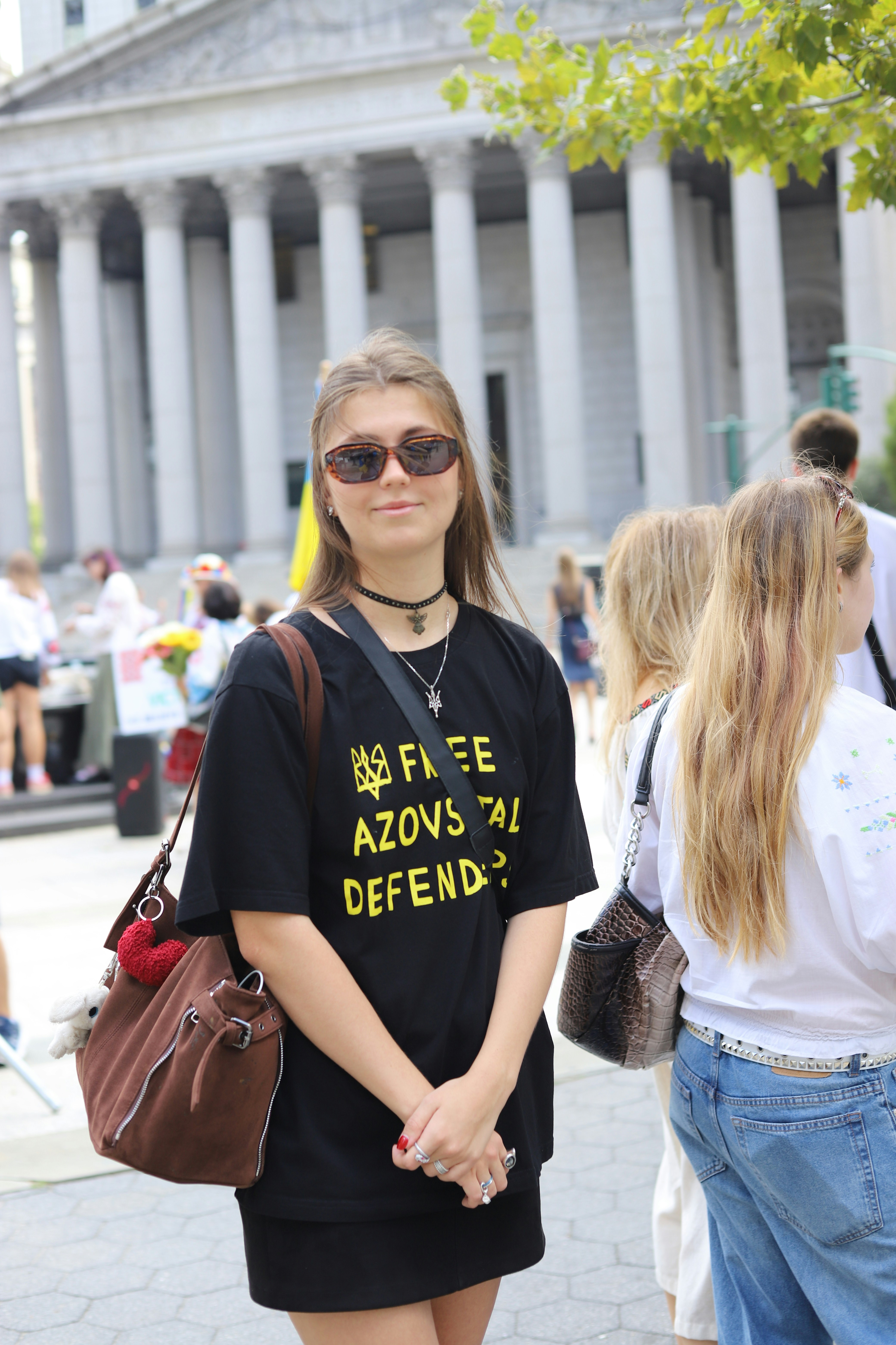 A woman in a black t-shirt with yellow text standing in a plaza