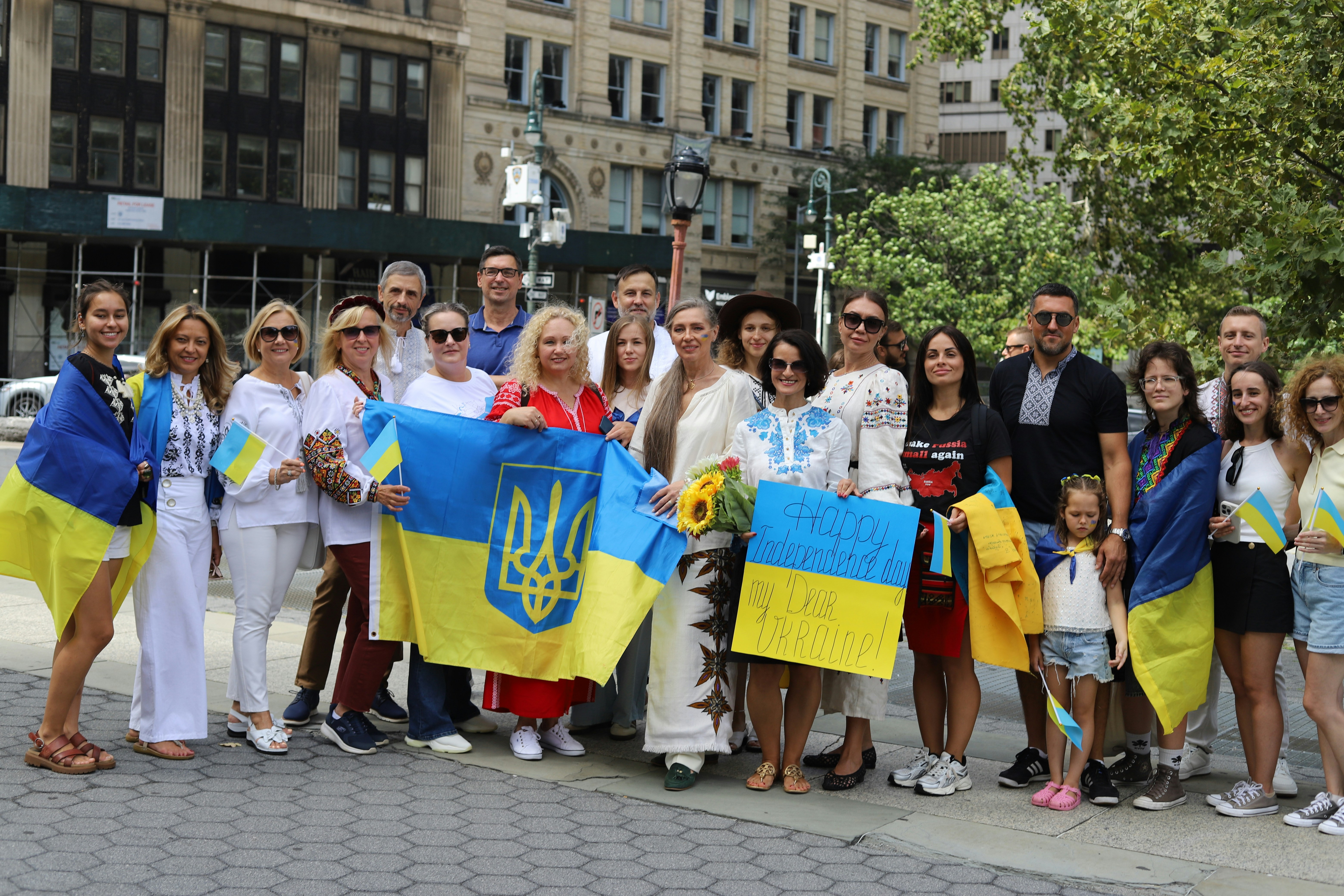 A group of people holding Ukrainian flags and a sign in a city square