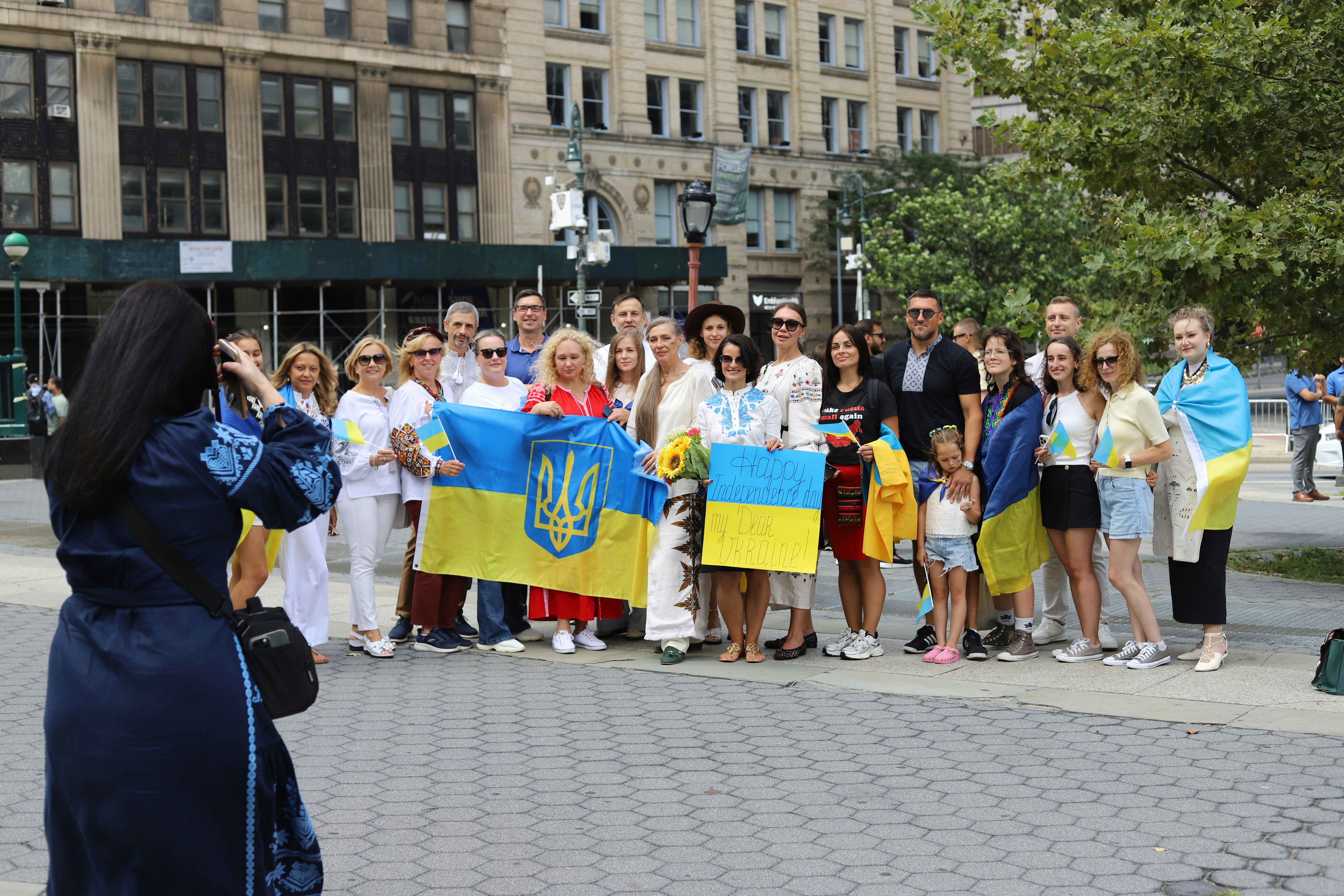 A group of people holding Ukrainian flags and a sign in a city square