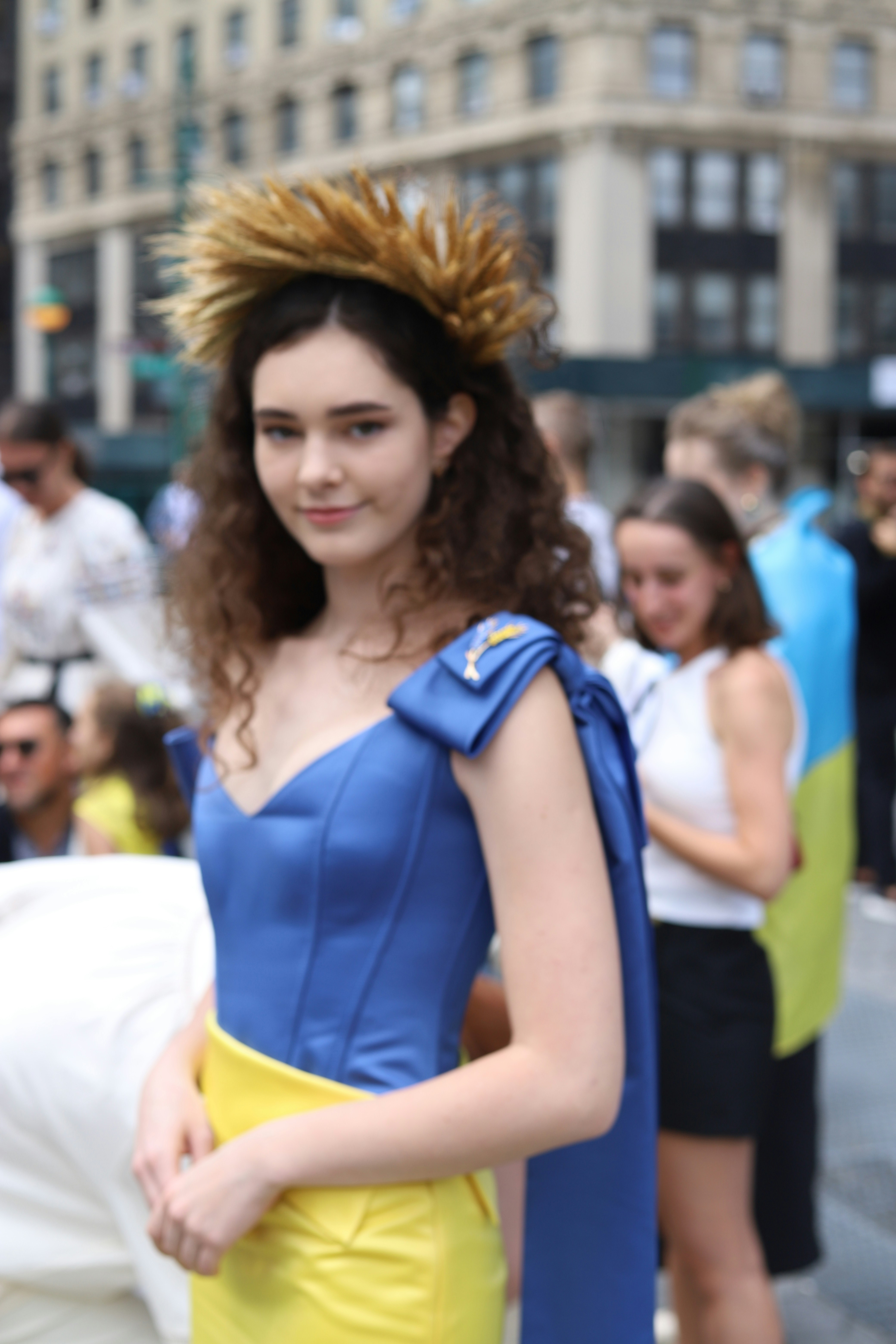 A woman with curly hair wearing a gold crown and blue and yellow dress