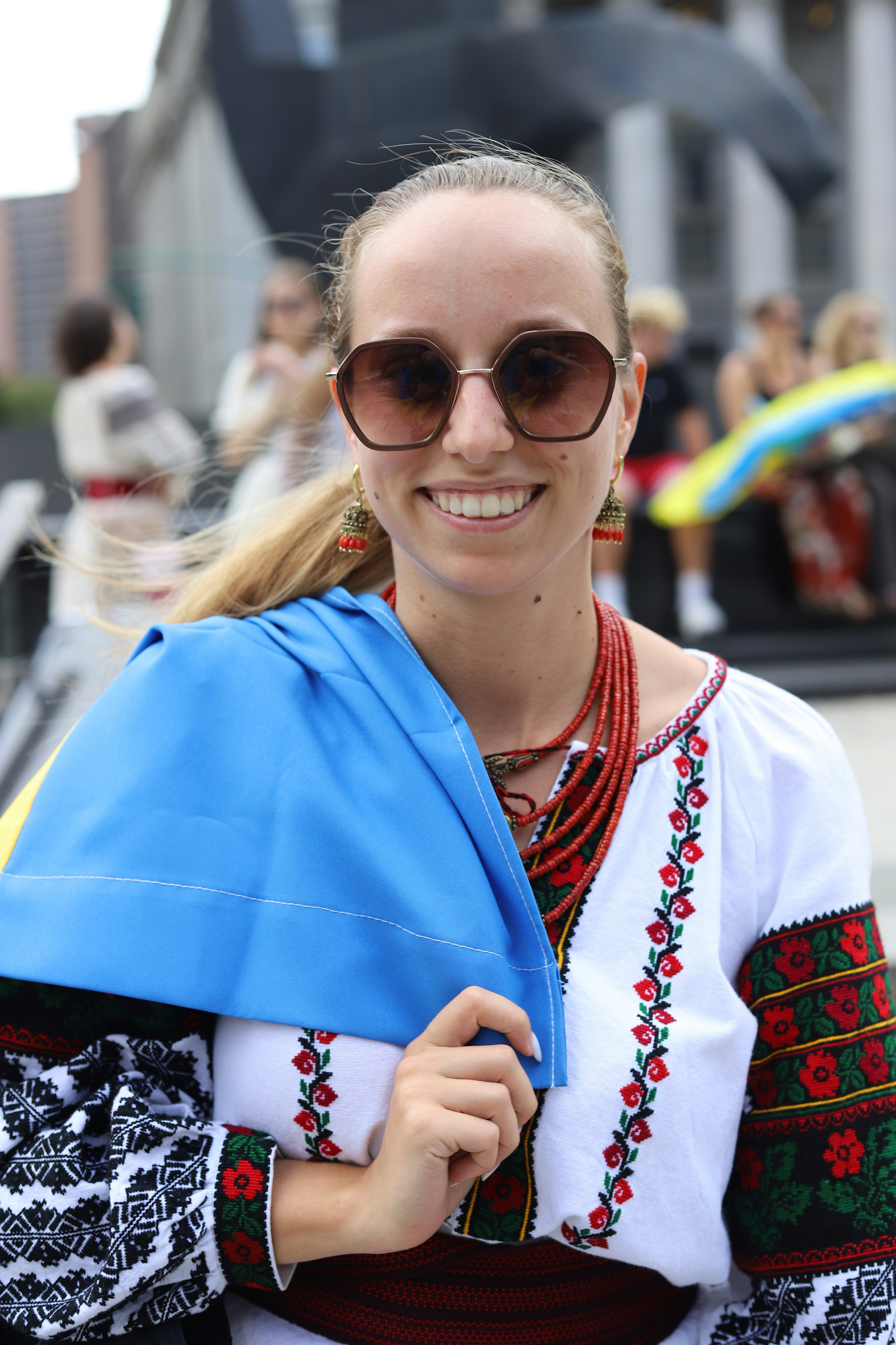 A smiling woman wearing a traditional embroidered vyshyvanka and red beaded necklace