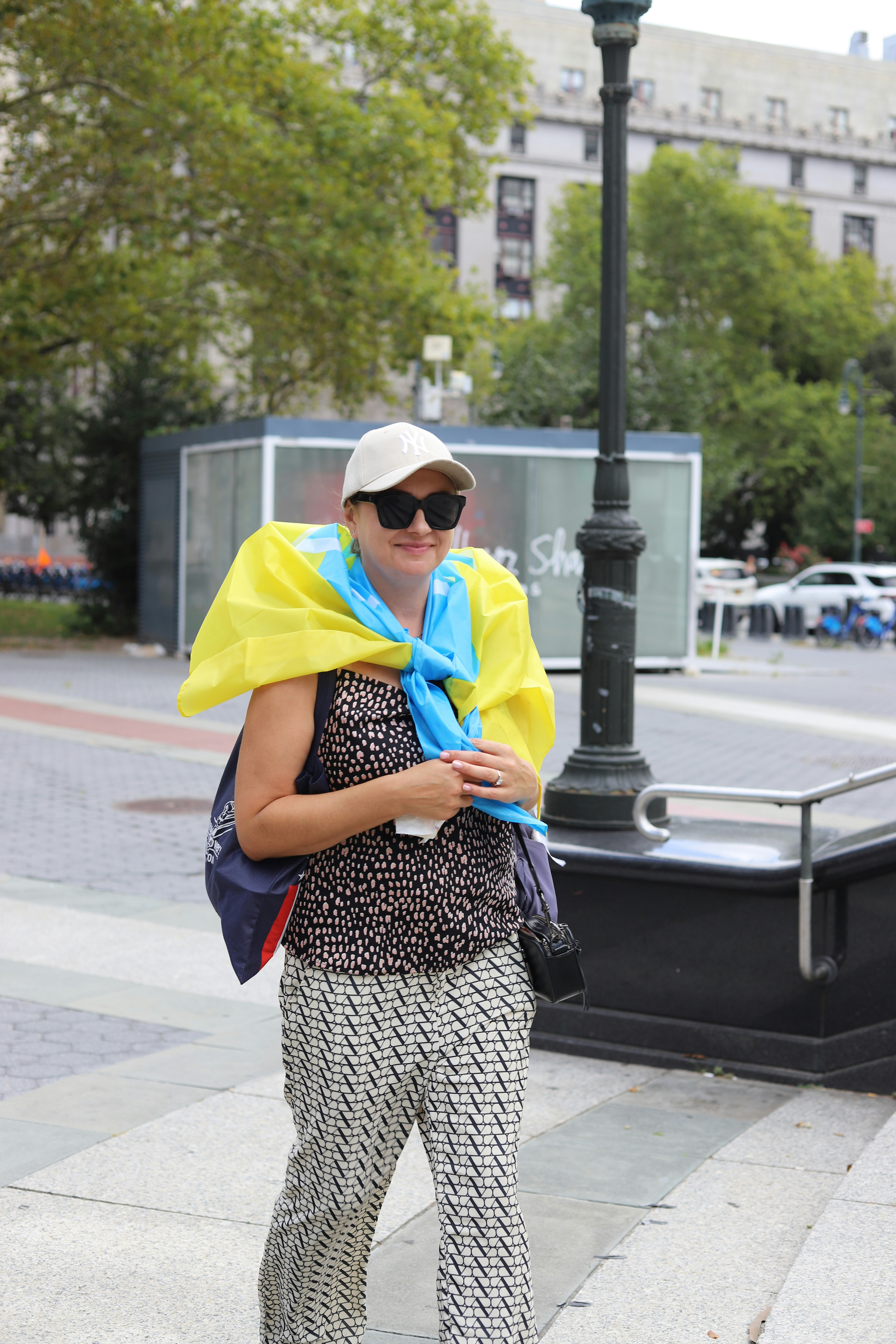 A woman wearing patterned pants and a blue and yellow flag draped over her shoulders