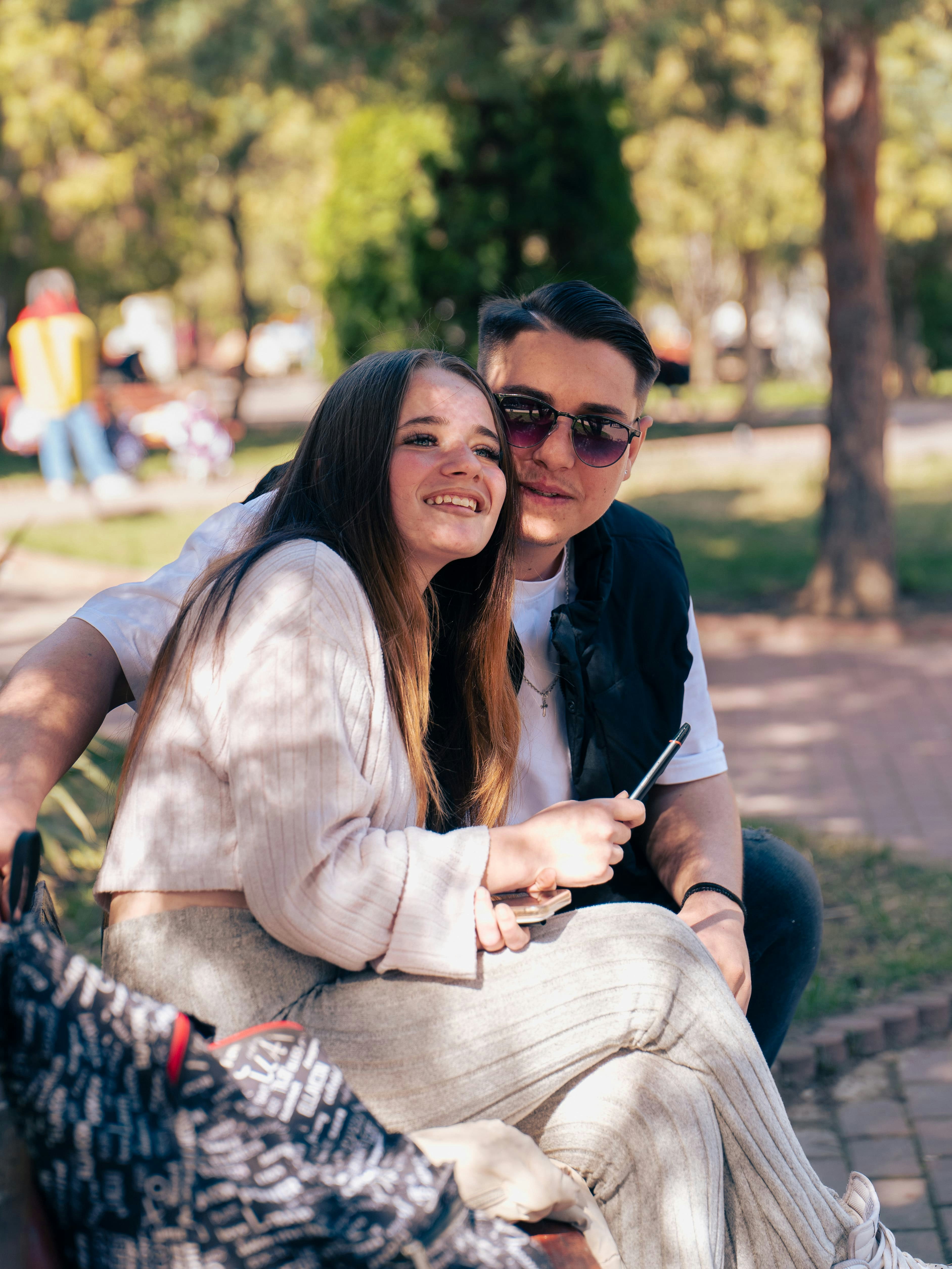 A young woman and a man sitting together on a park bench