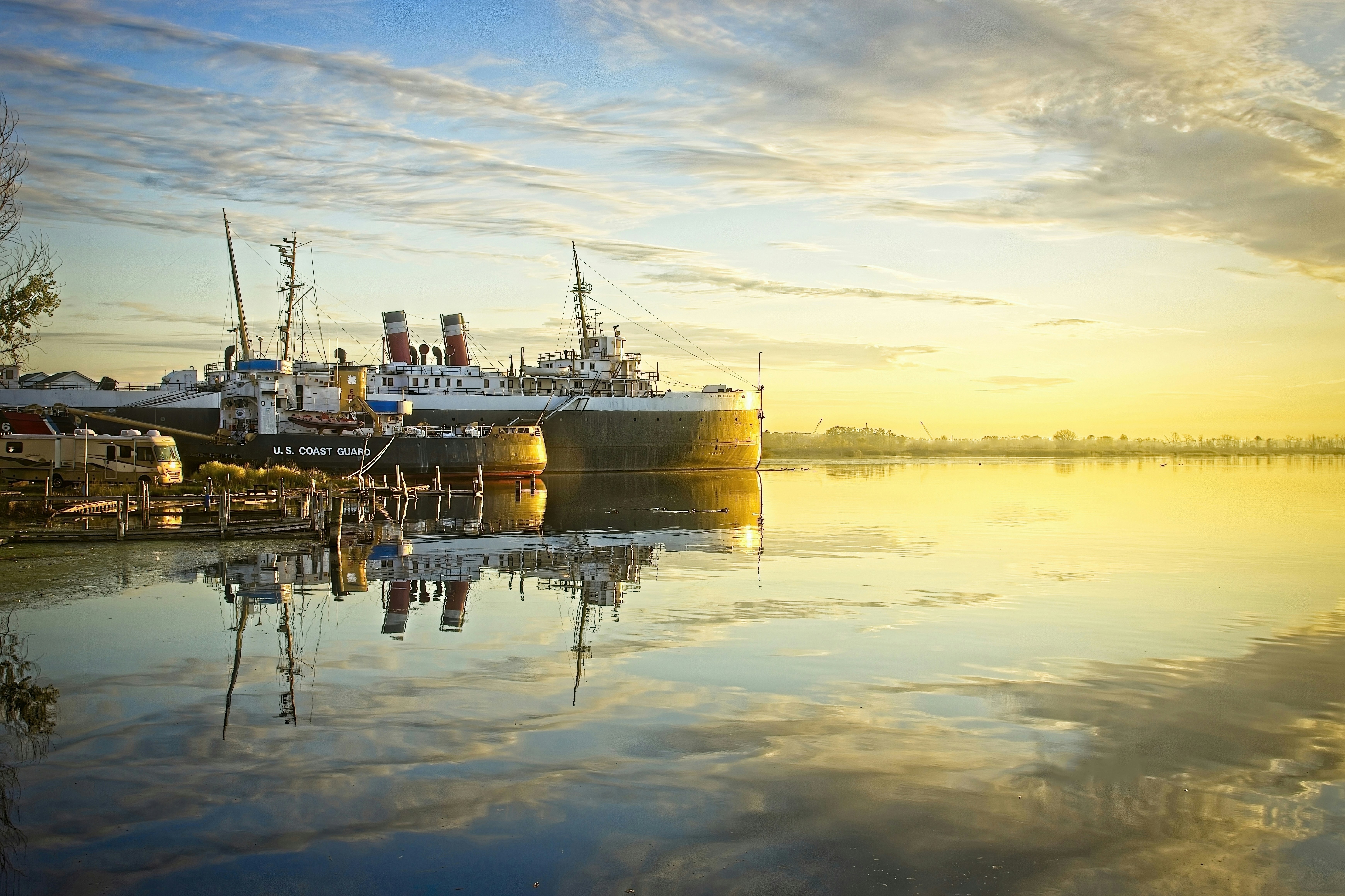 A U.S. Coast Guard ship and a large vessel moored on calm water