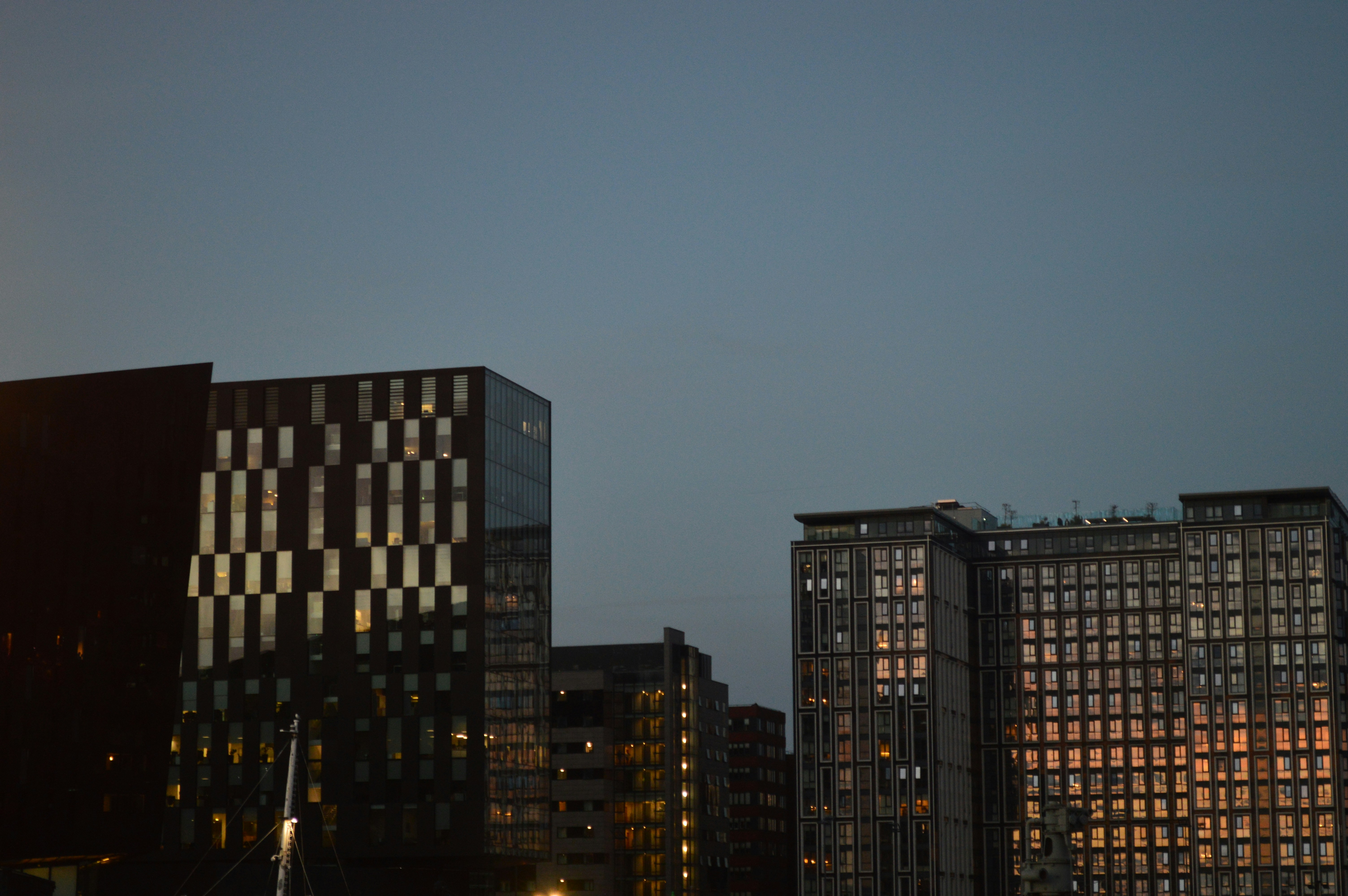 Modern apartment buildings with illuminated windows against a clear evening sky