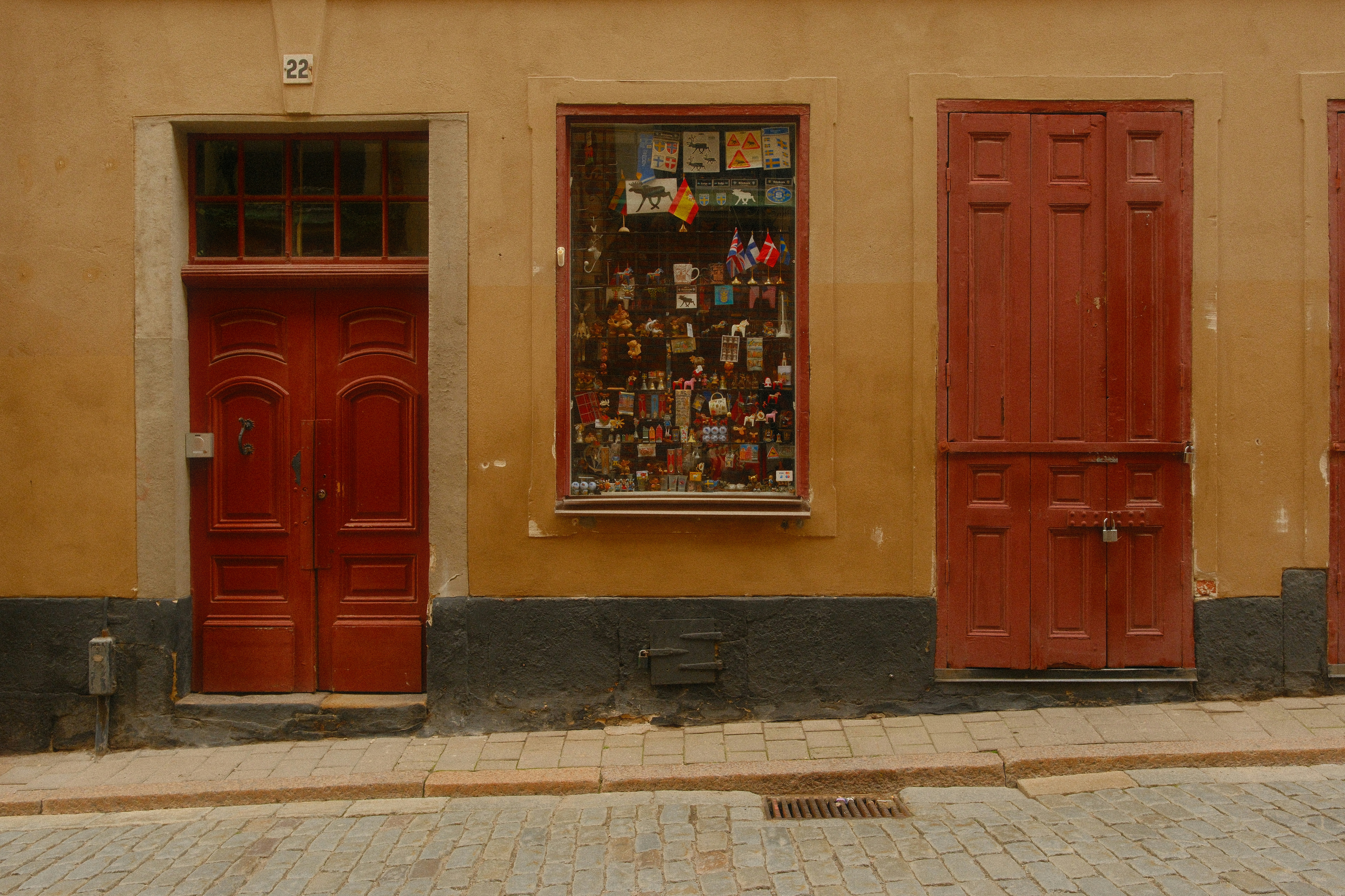 Two red doors and a shop window filled with souvenirs on a cobblestone street