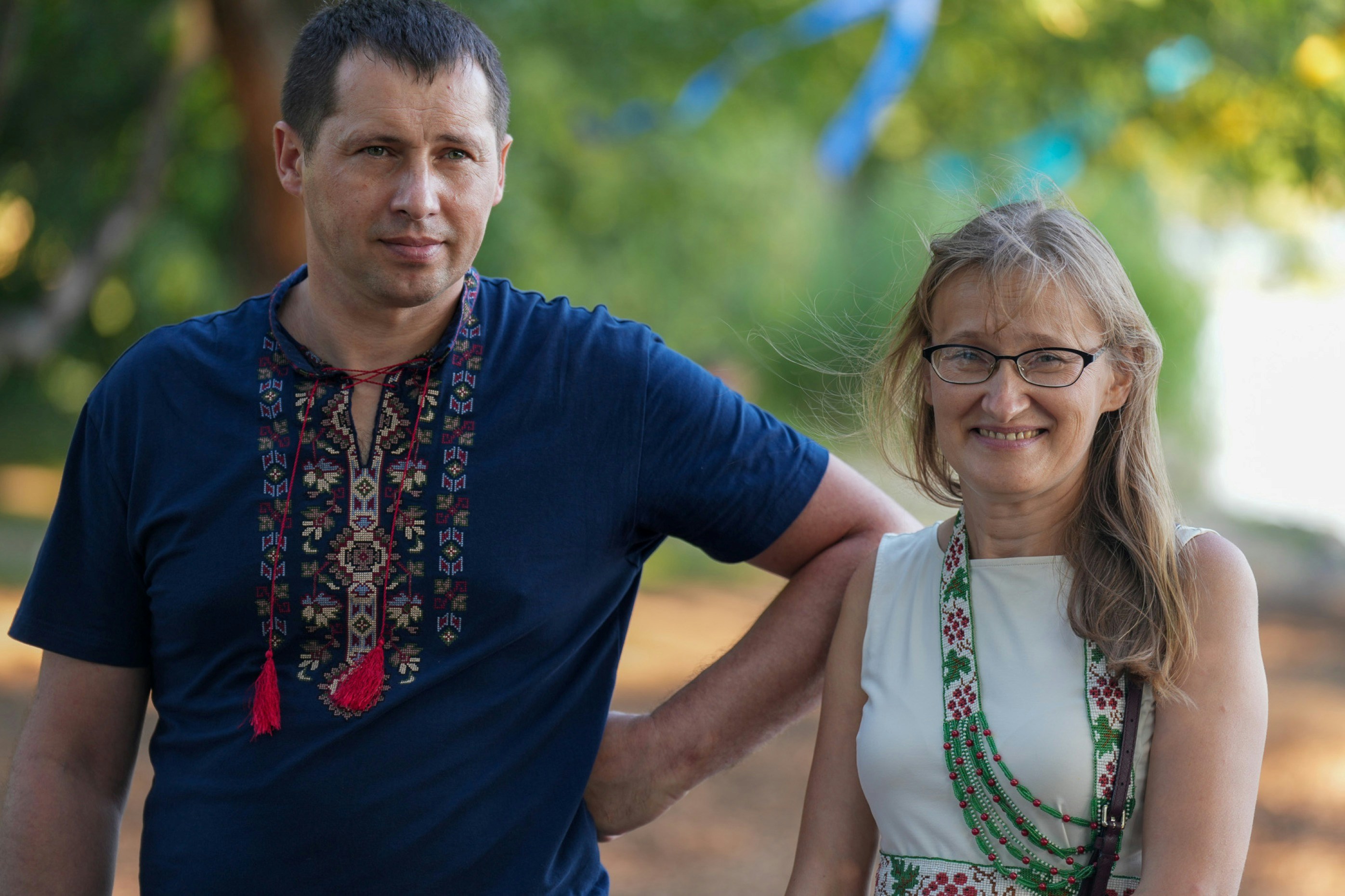 A man in a blue embroidered shirt and a woman in a white dress