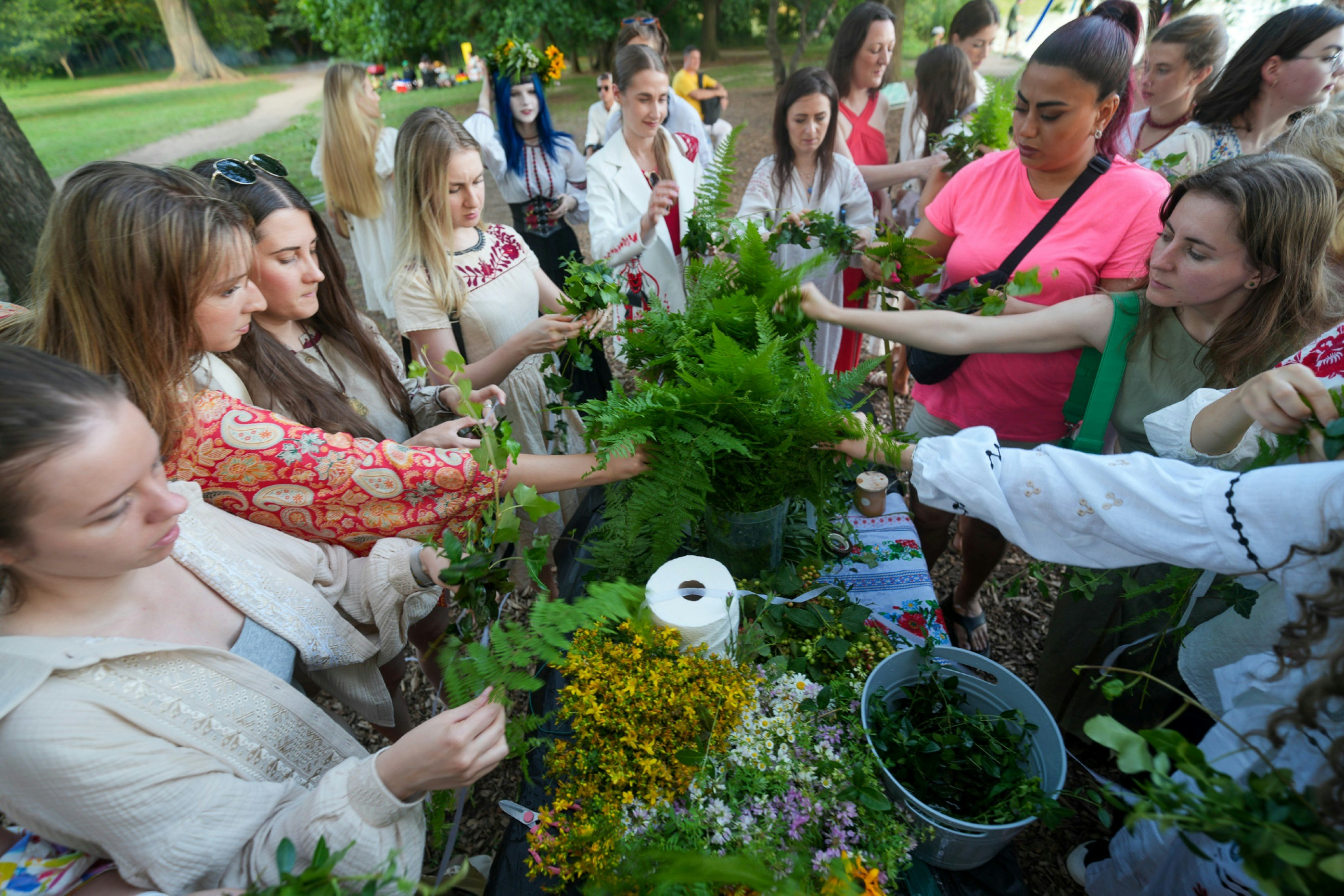 A group of women weaving flower crowns and garlands at an outdoor workshop