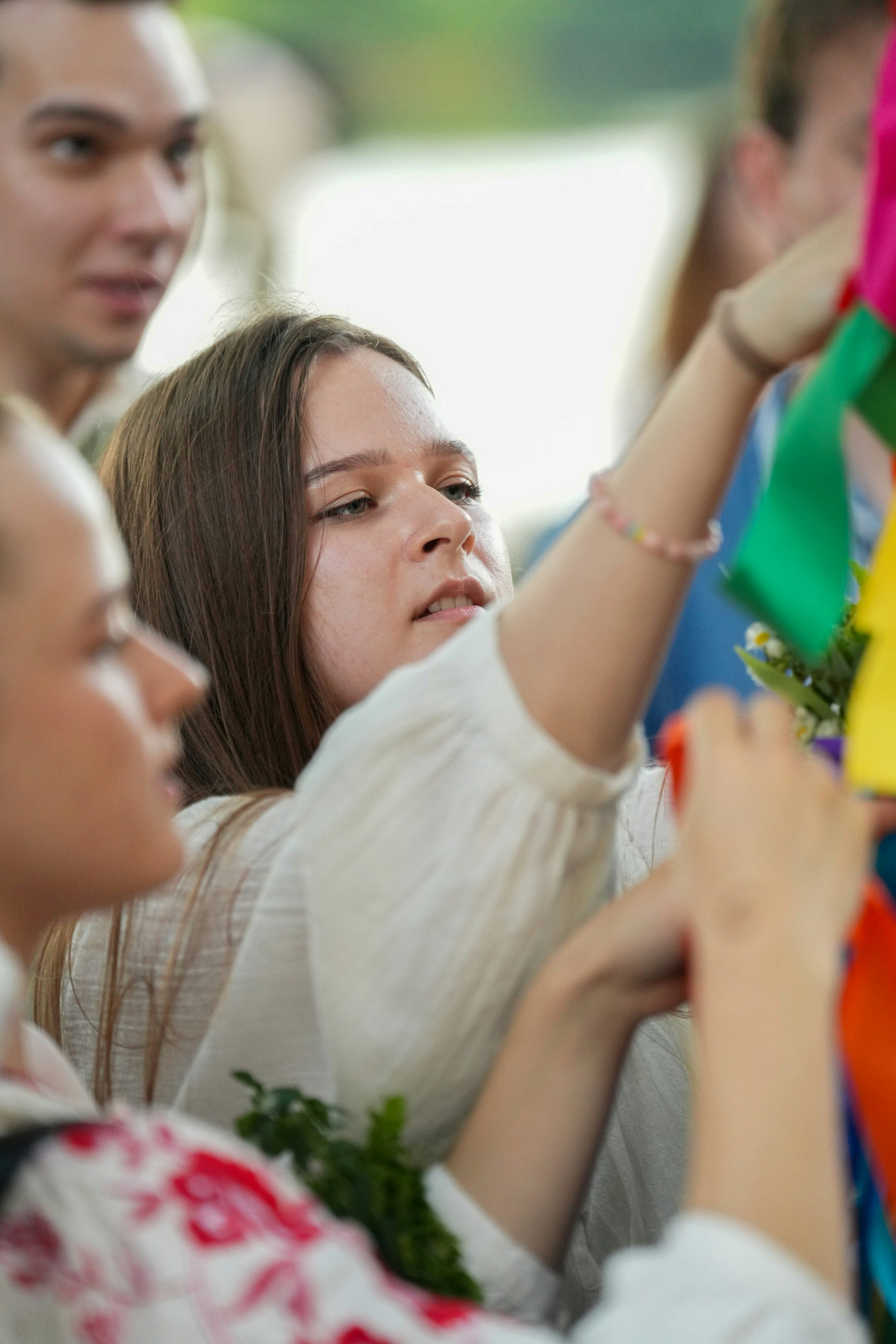 A woman in a white blouse tying colorful ribbons to a decorative structure