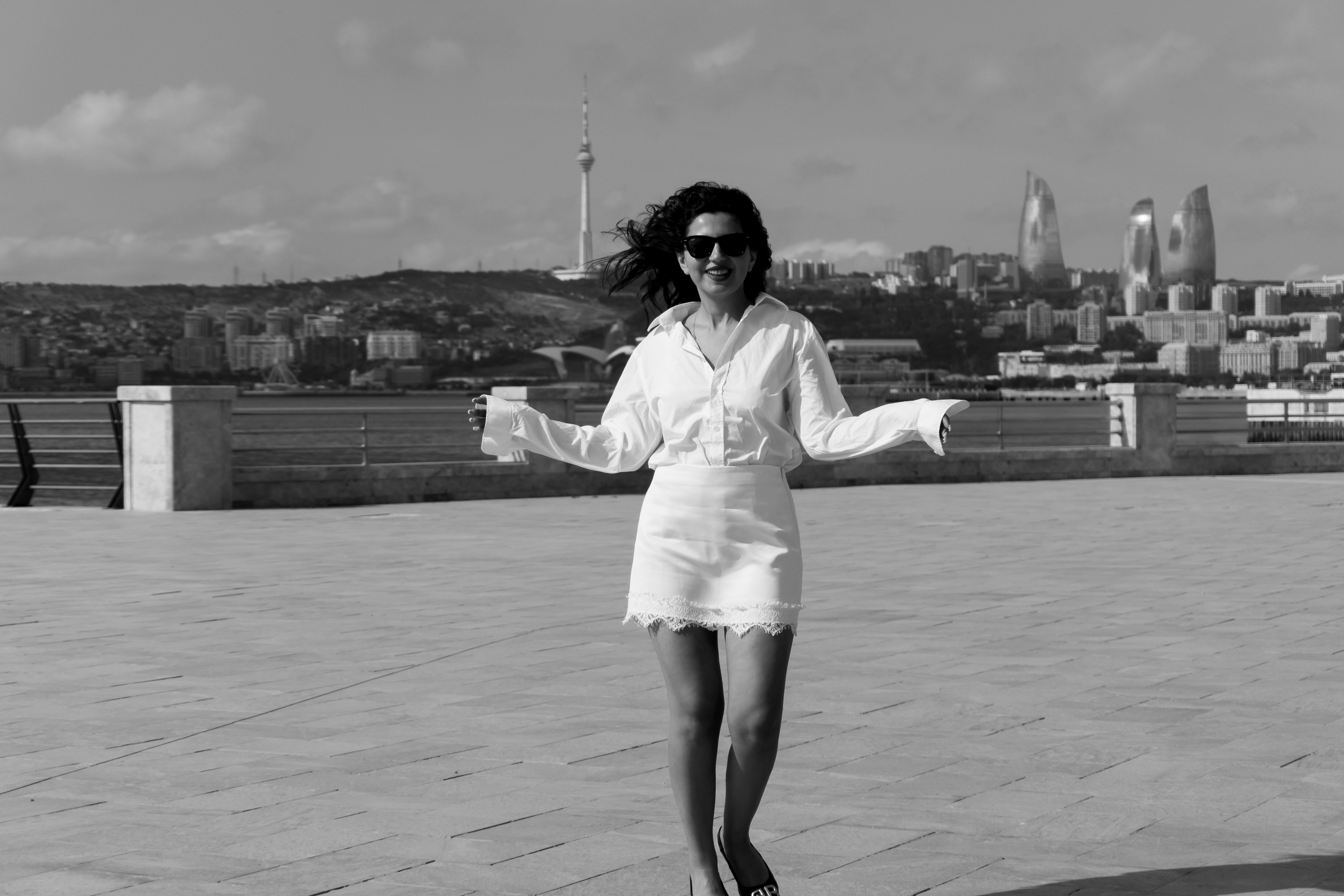 A woman in a white shirt and skirt walking on a Baku promenade