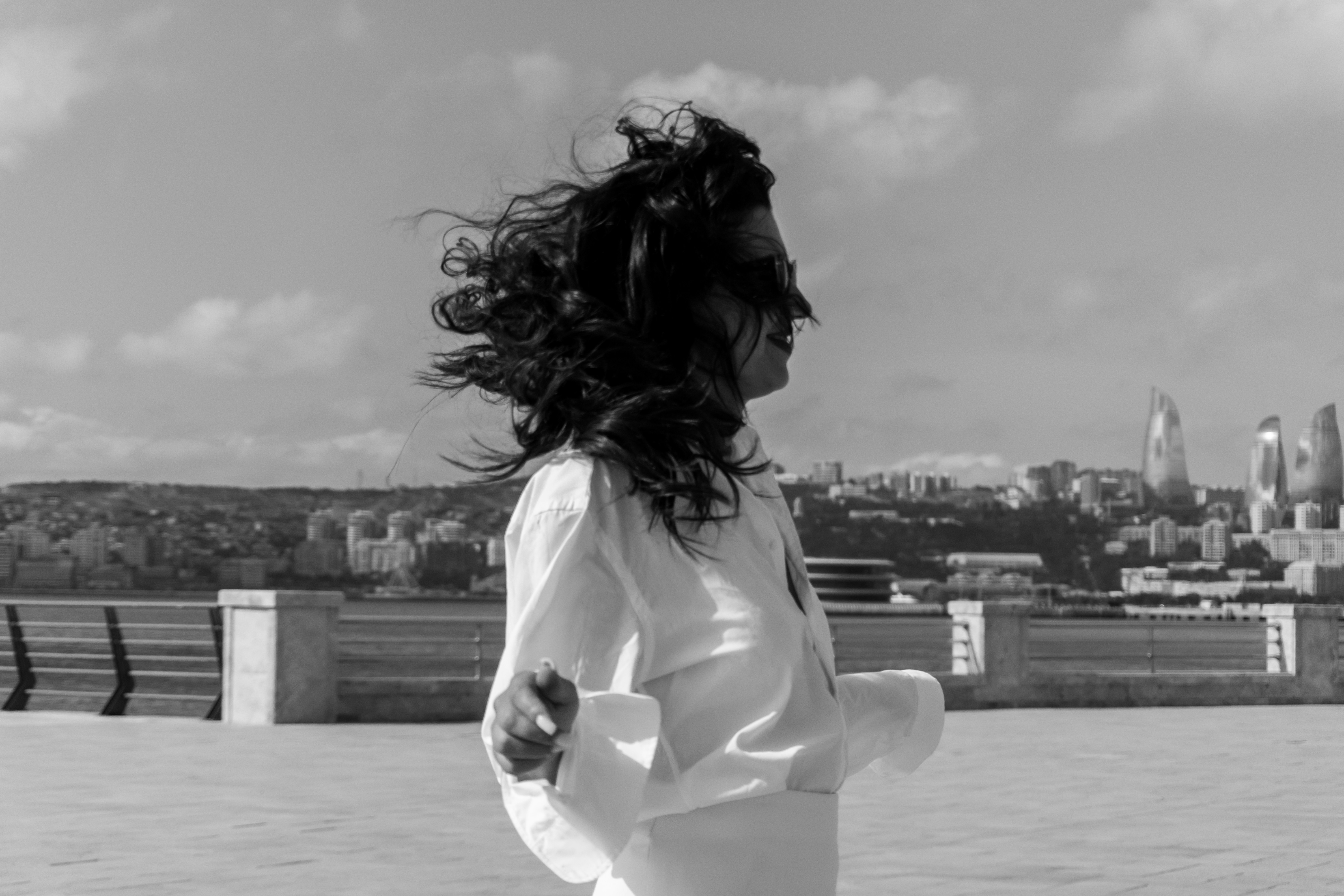 A woman with windblown hair in a white shirt on the Baku Boulevard