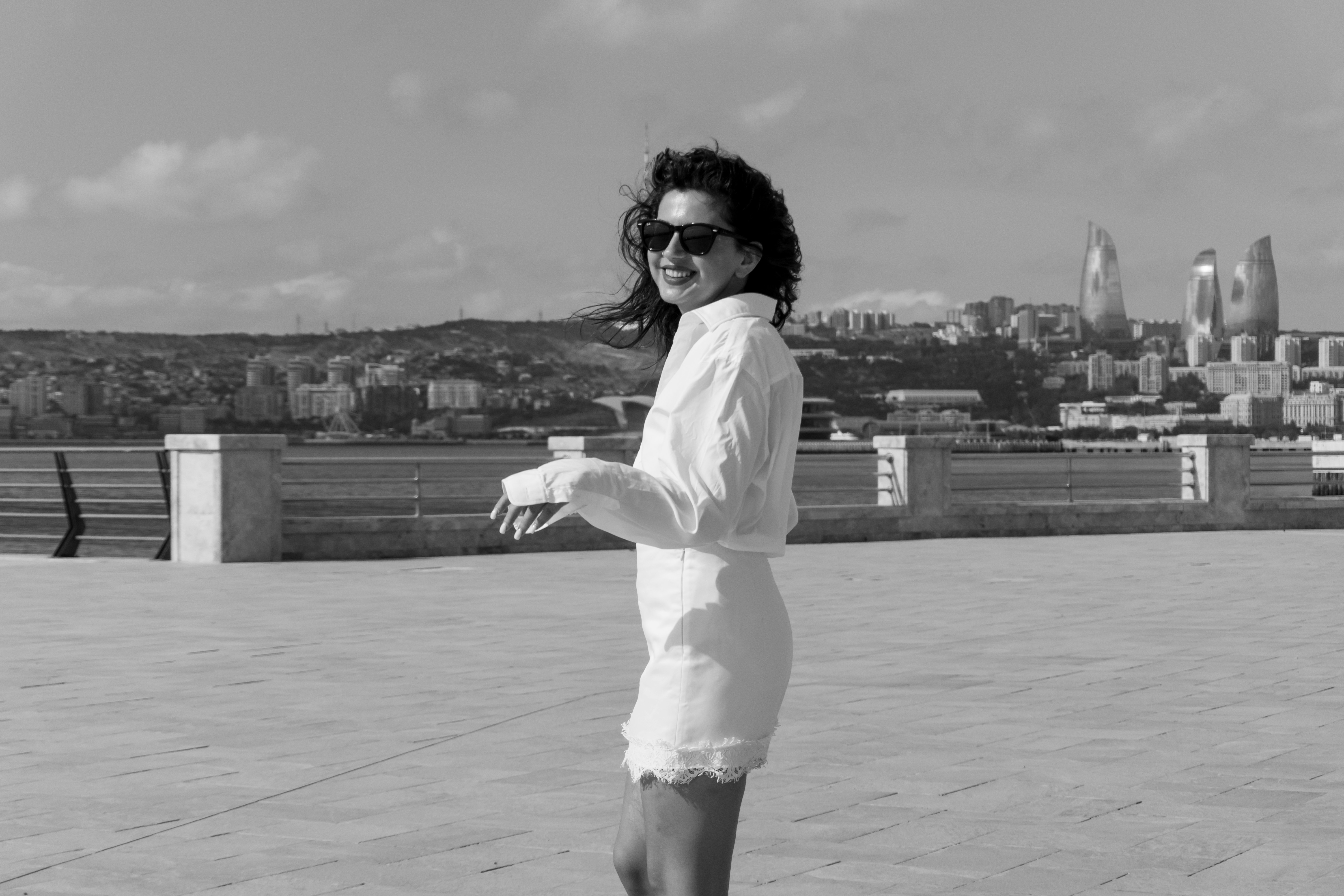 A woman in a white shirt and skirt on a waterfront promenade in Baku