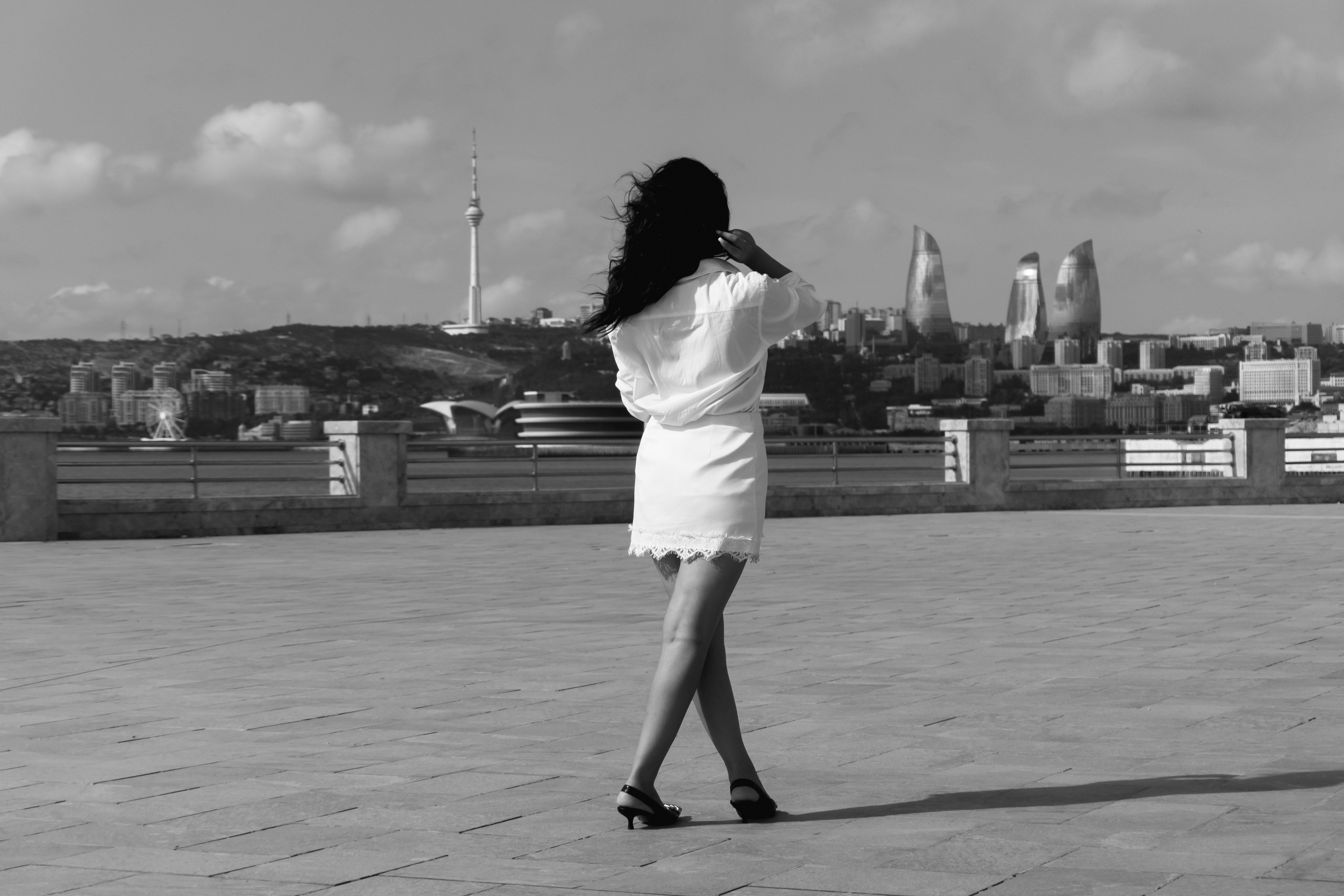 A woman in a white dress walking on a stone promenade in Baku