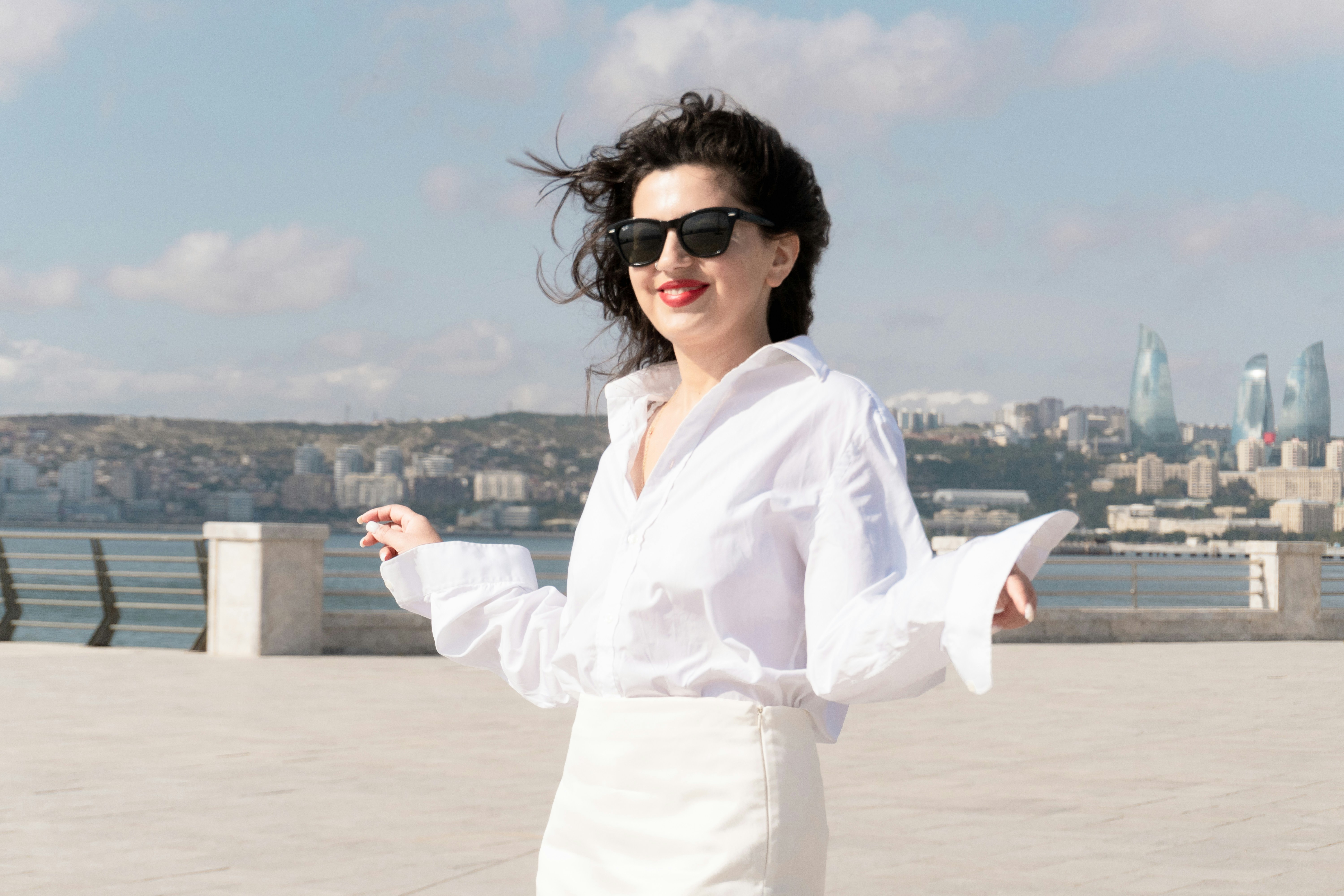 A woman in a white shirt and sunglasses on the Baku Boulevard waterfront