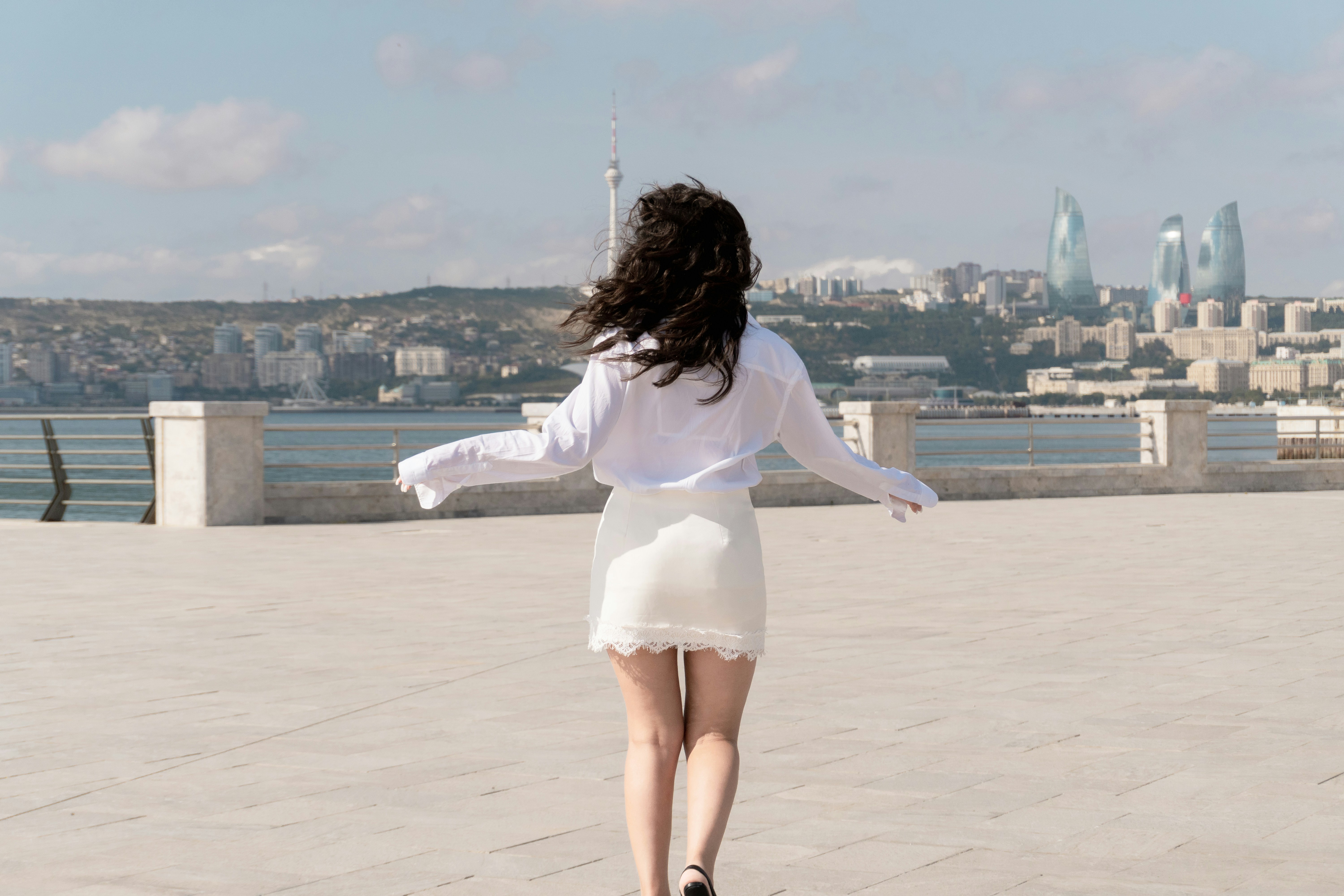 A woman in a white shirt and skirt walking along the Baku Boulevard