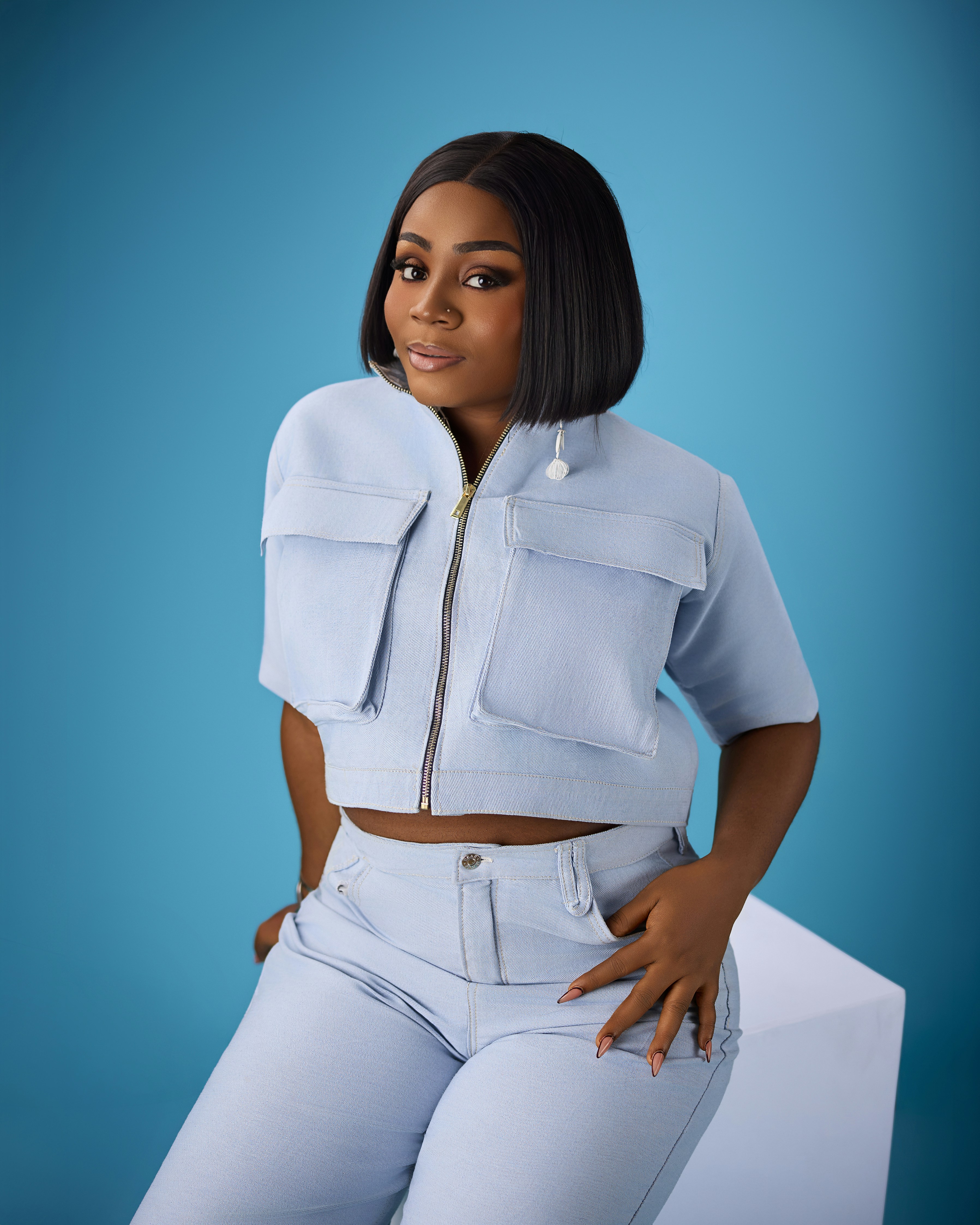 A woman with a black bob haircut wearing a light blue denim outfit