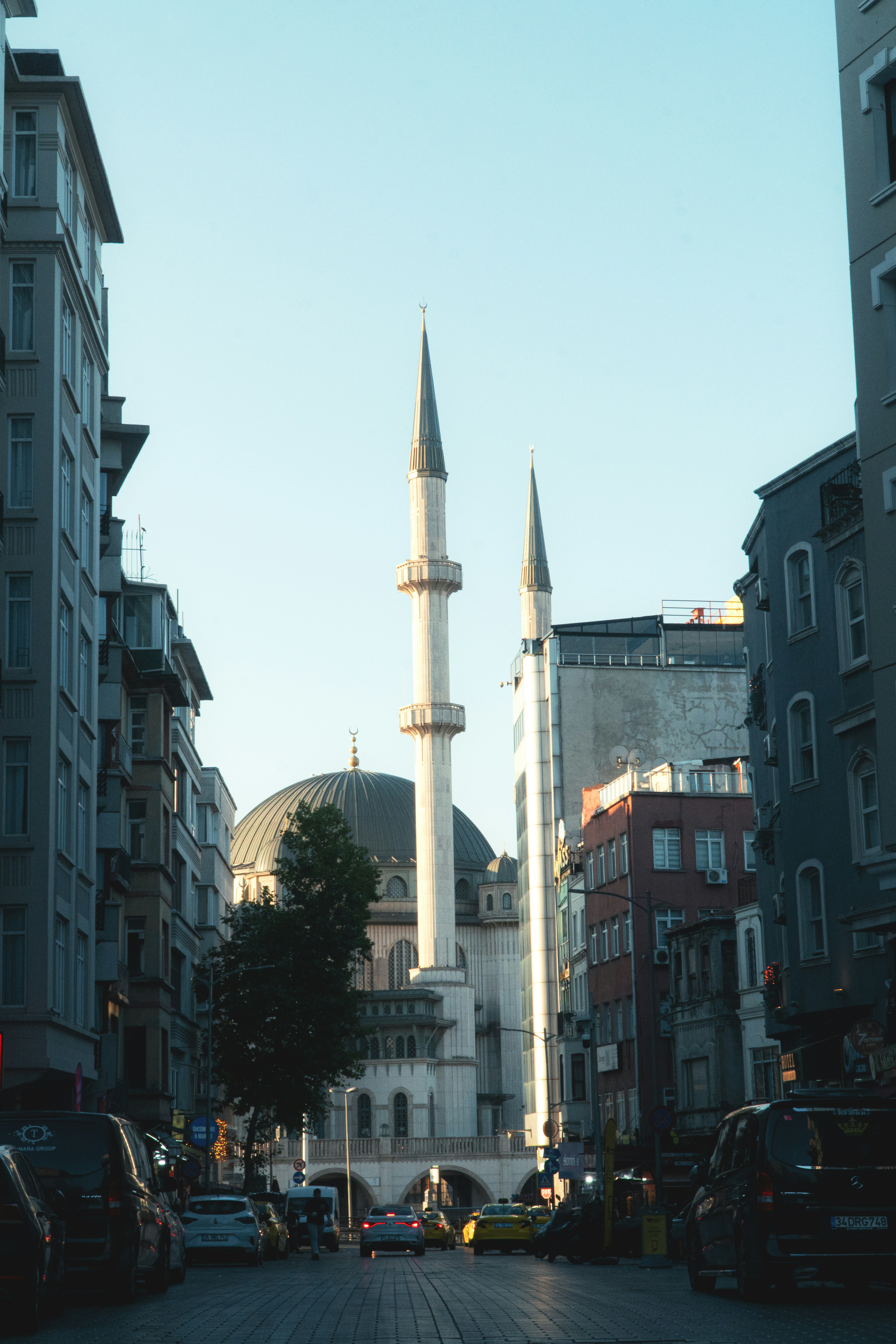 A mosque with a dome and minarets at the end of a city street