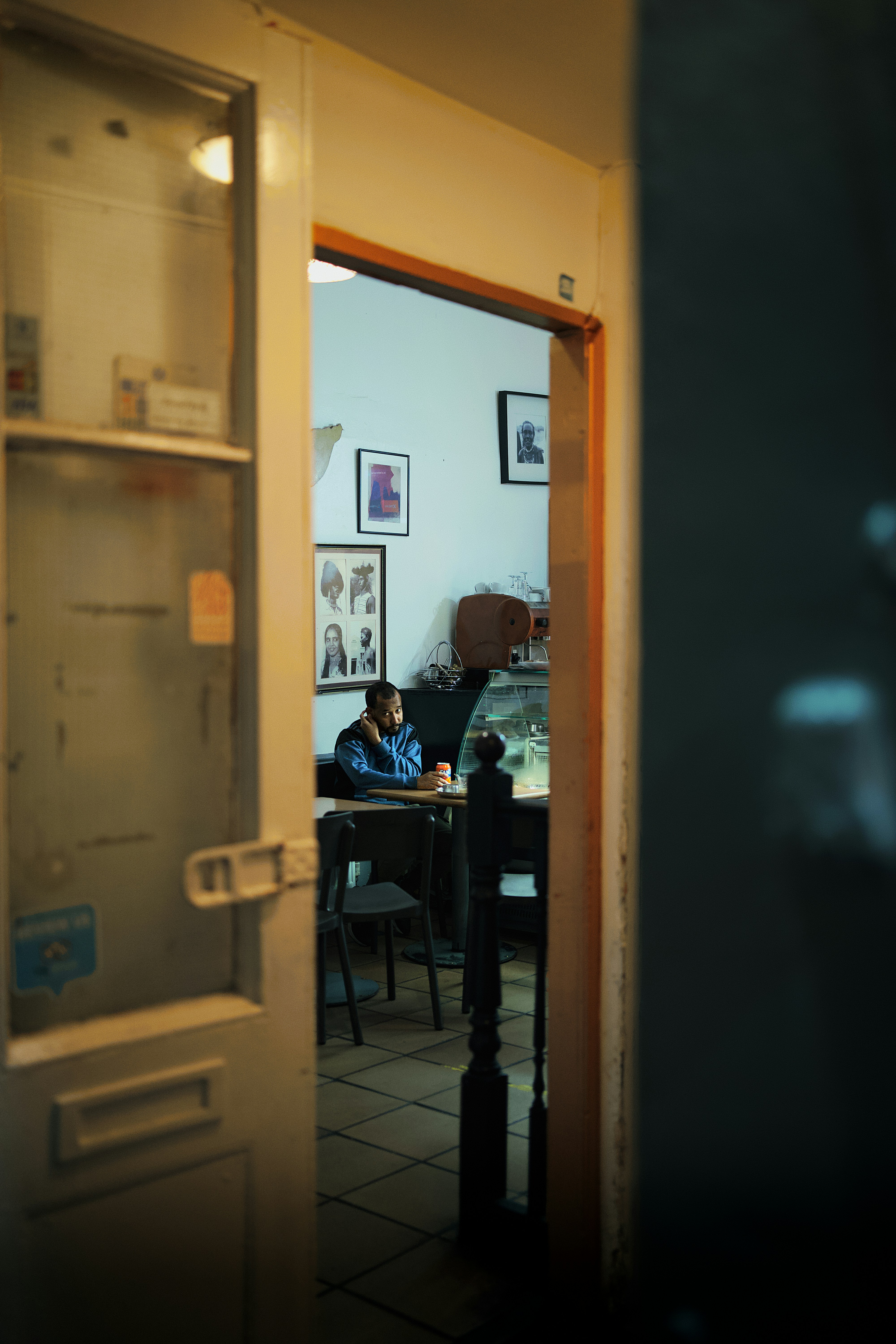 A man in a blue jacket sitting at a table in a cafe
