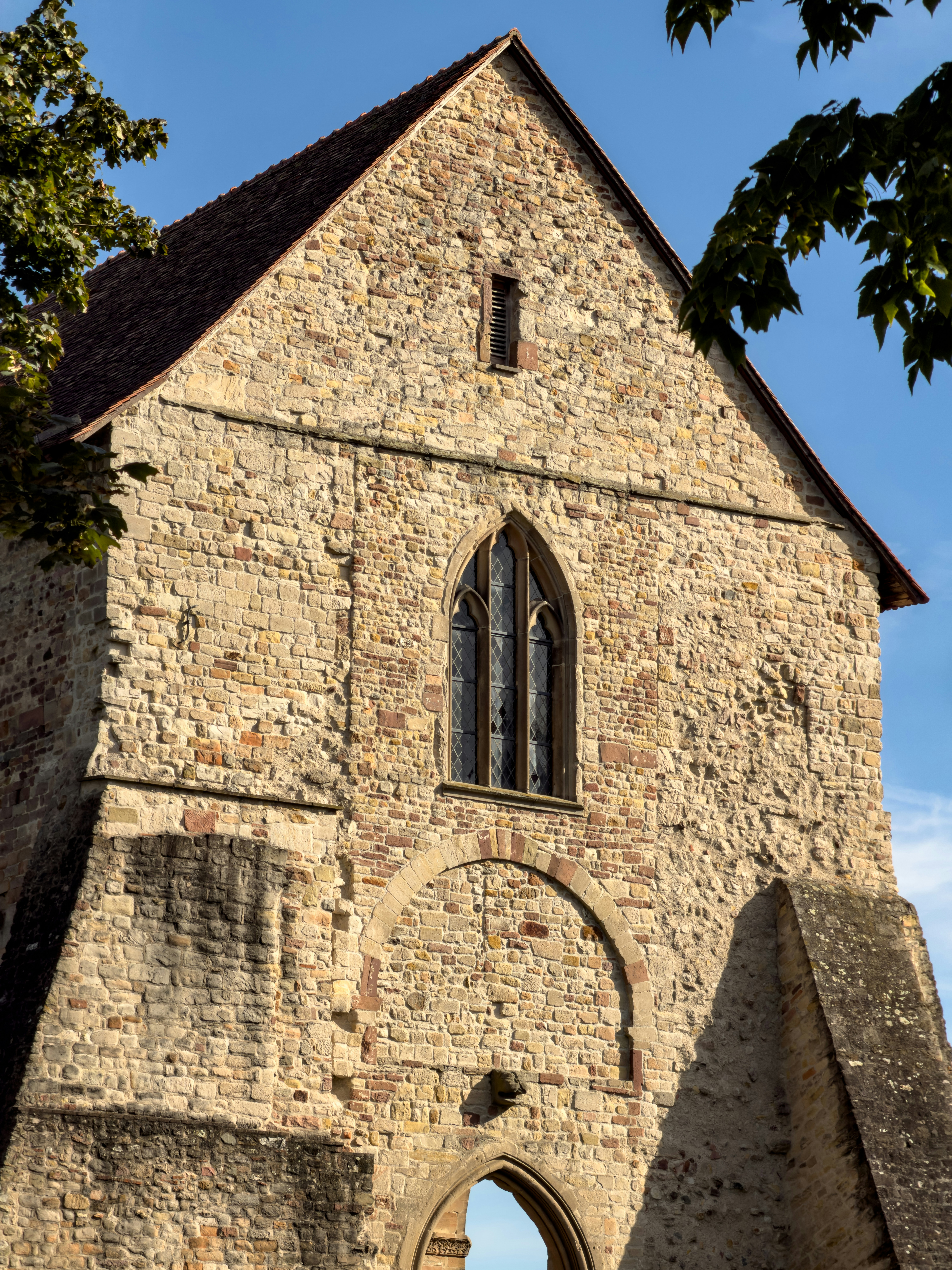 A medieval stone church facade with a pointed arch window and buttresses