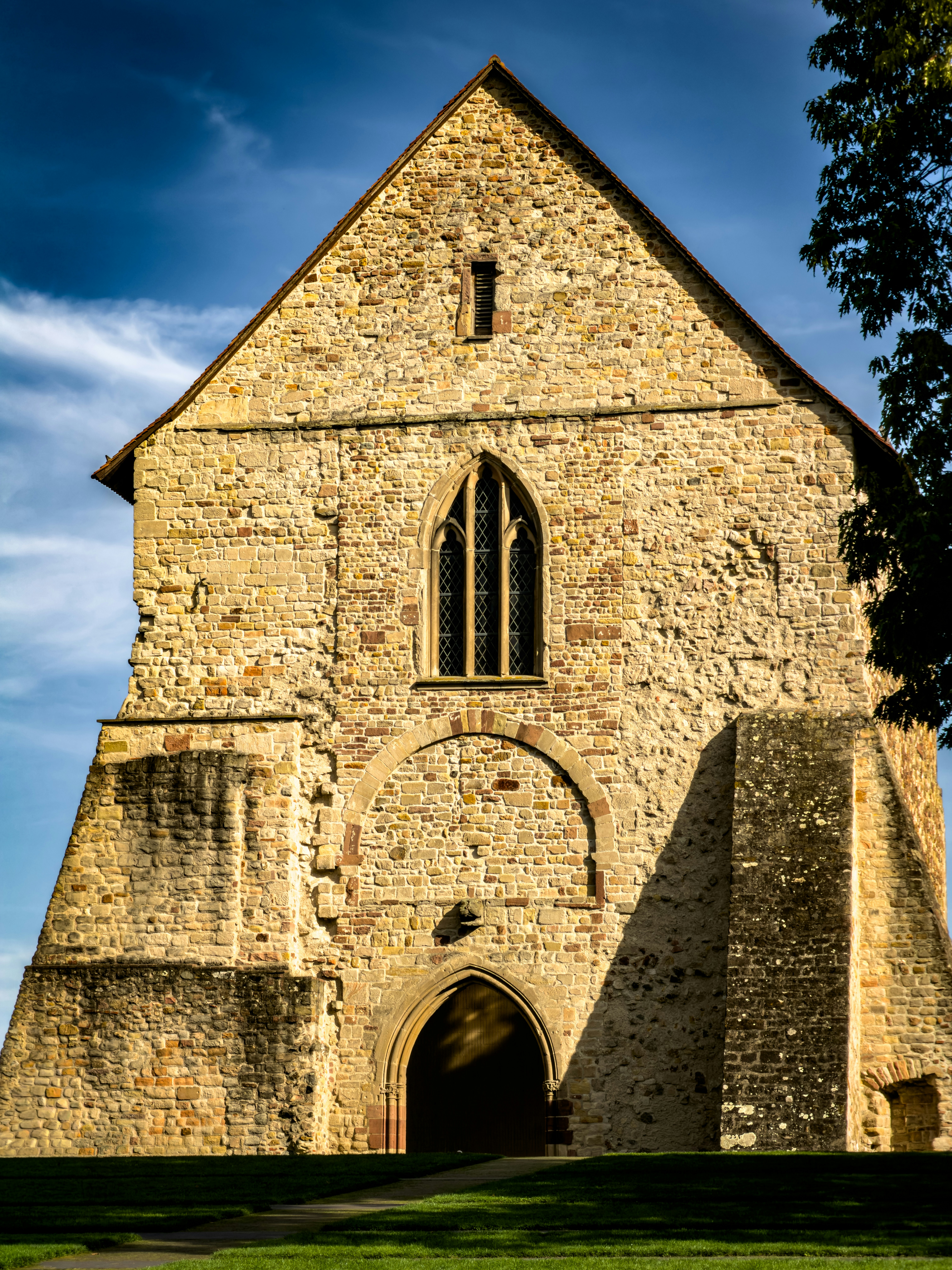 A stone church facade with a pointed arch window under a blue sky