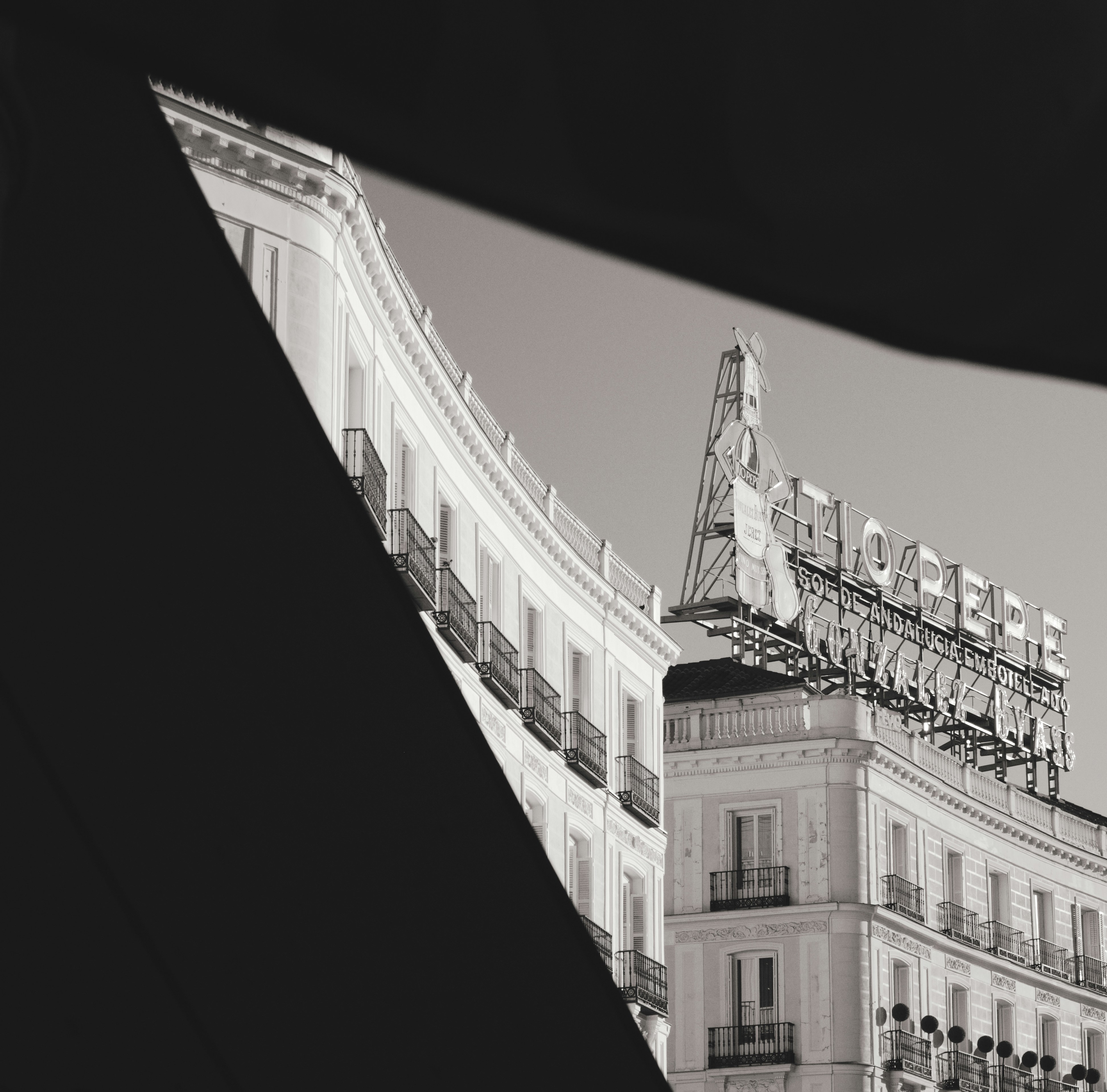 Tio Pepe sign atop a building in Madrid framed by dark architectural shadows