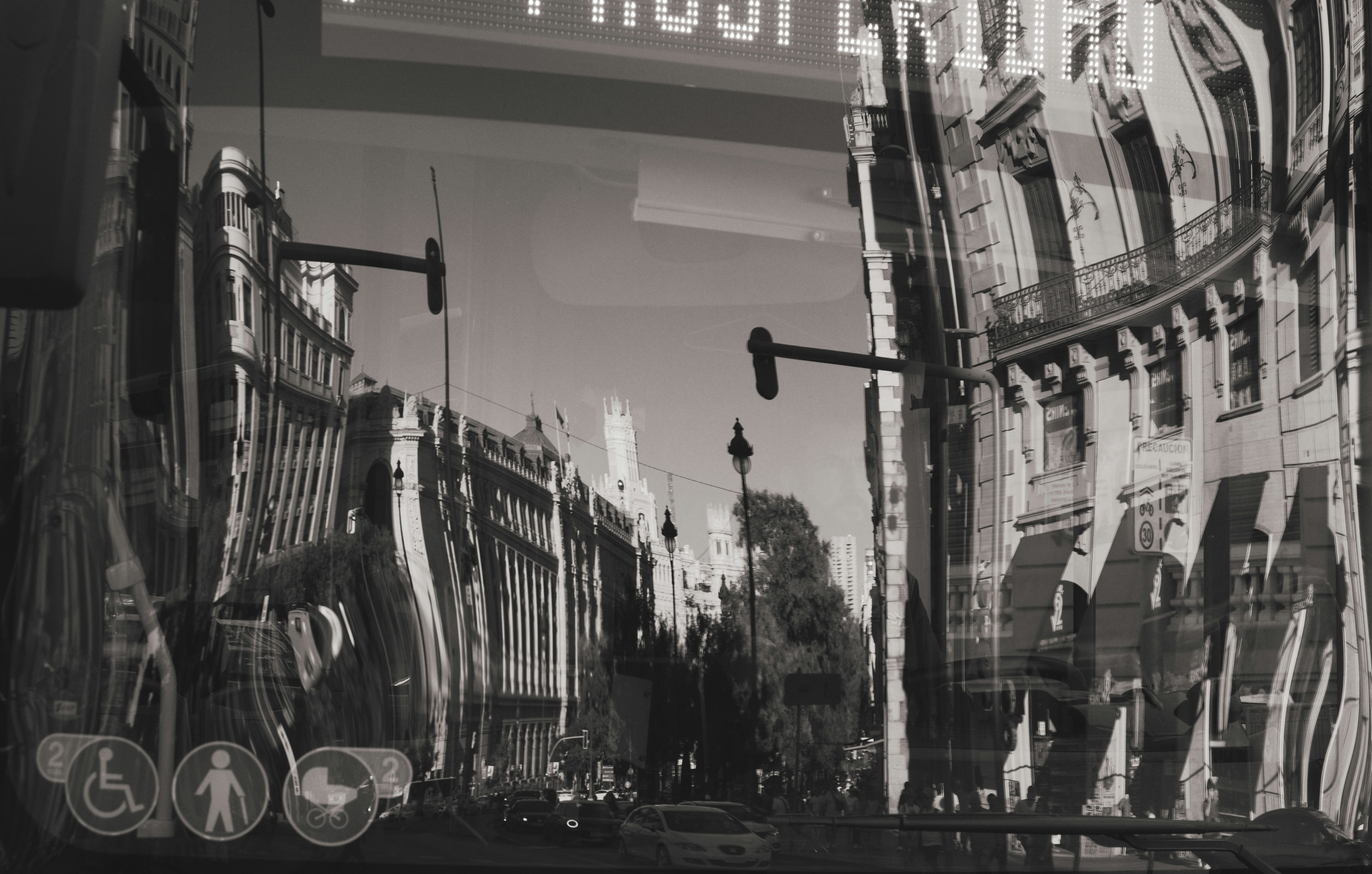 Reflection of city buildings and street traffic on a glass window with transit icons