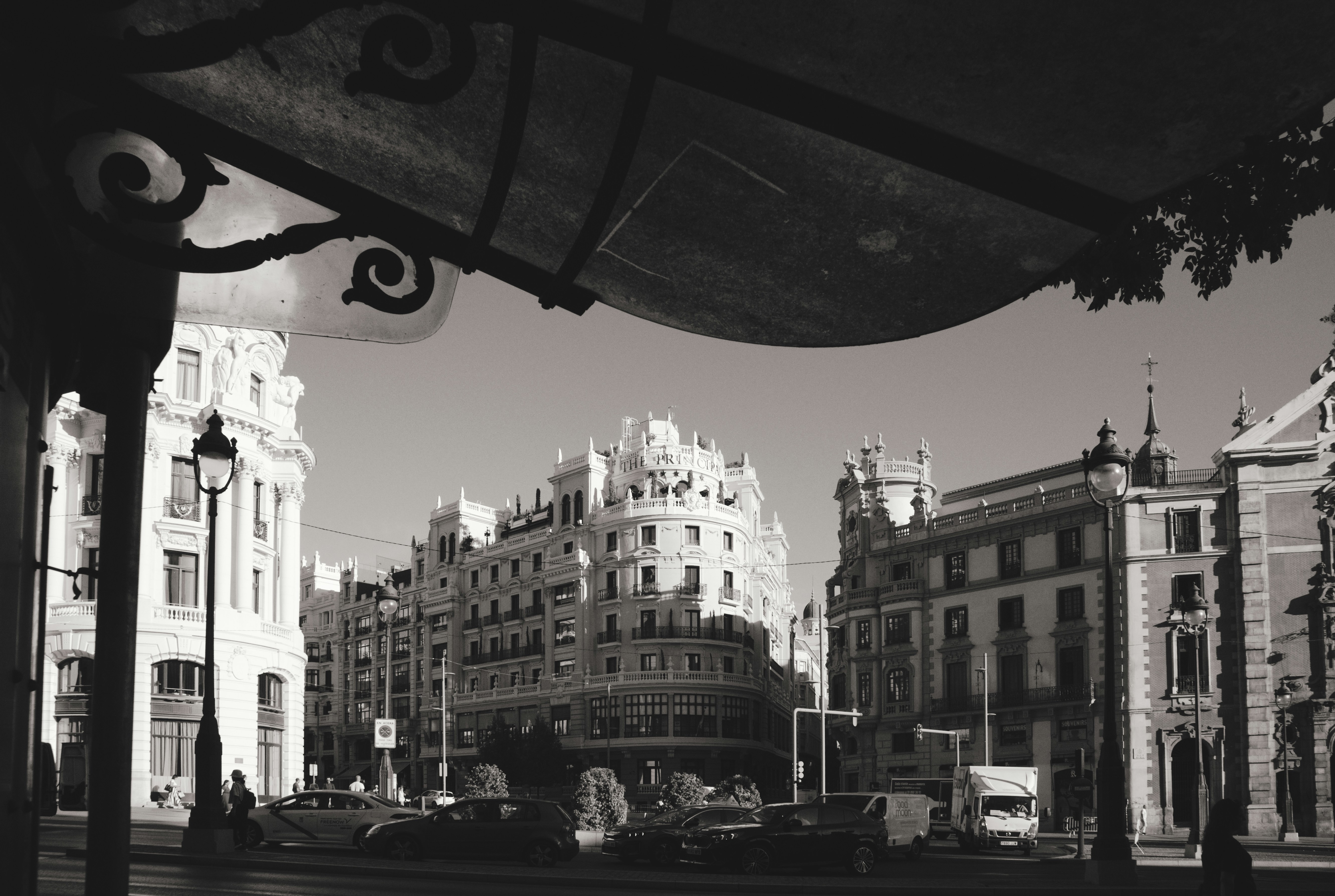 Black and white view of ornate buildings and cars on a street in Madrid