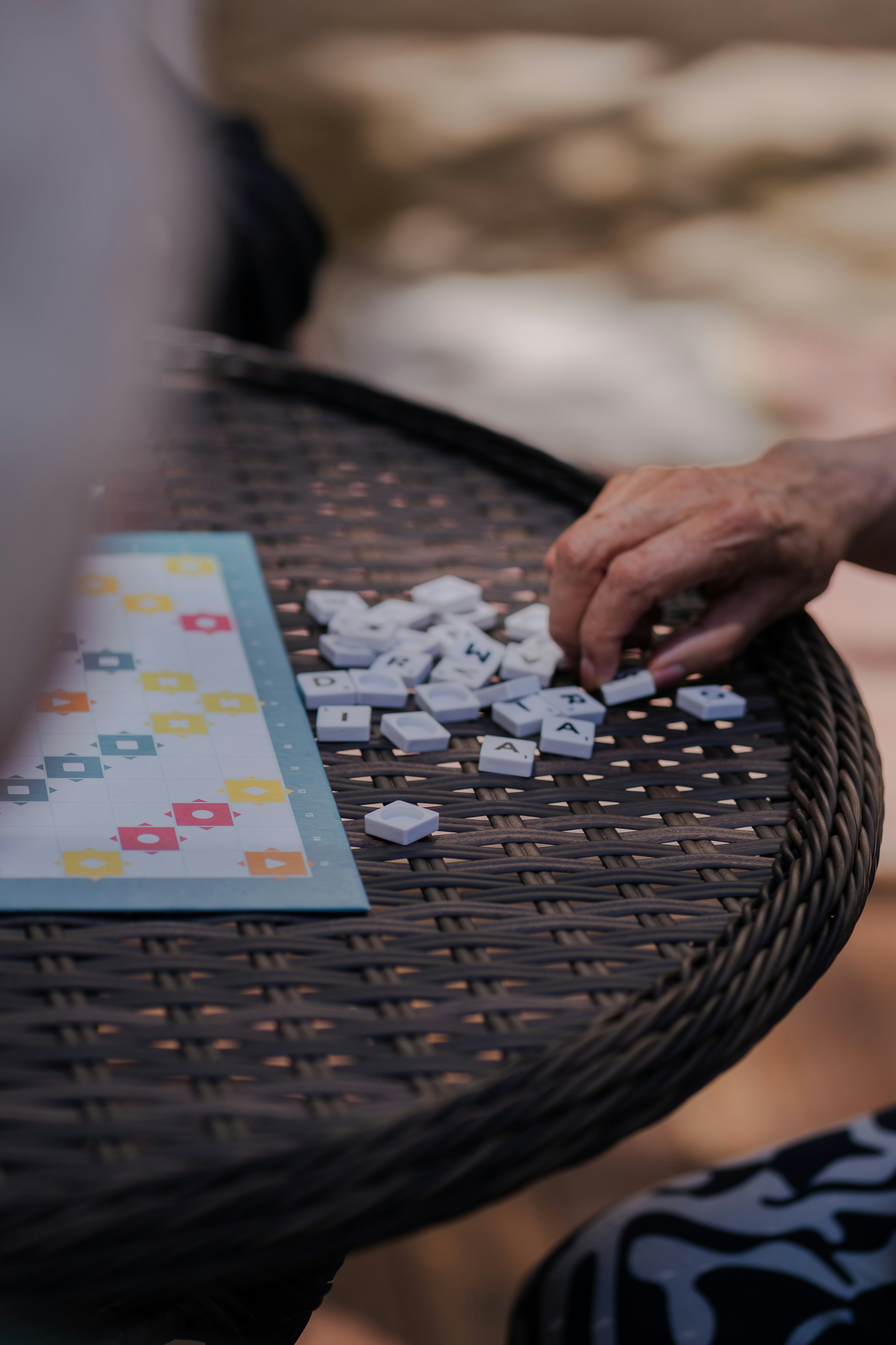 Eine Person, die ein Wortspiel mit Buchstabensteinen auf einem Weidentisch spielt