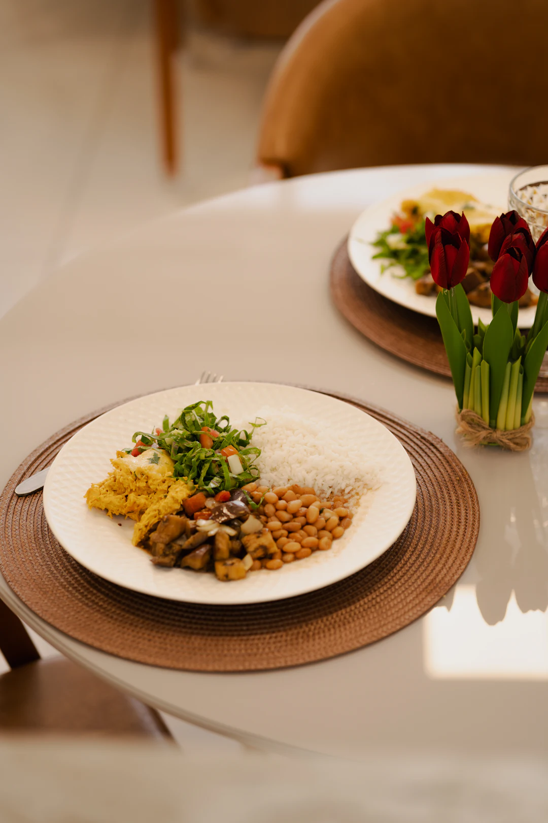 Prato com arroz, feijão, frango desfiado e salada em mesa posta