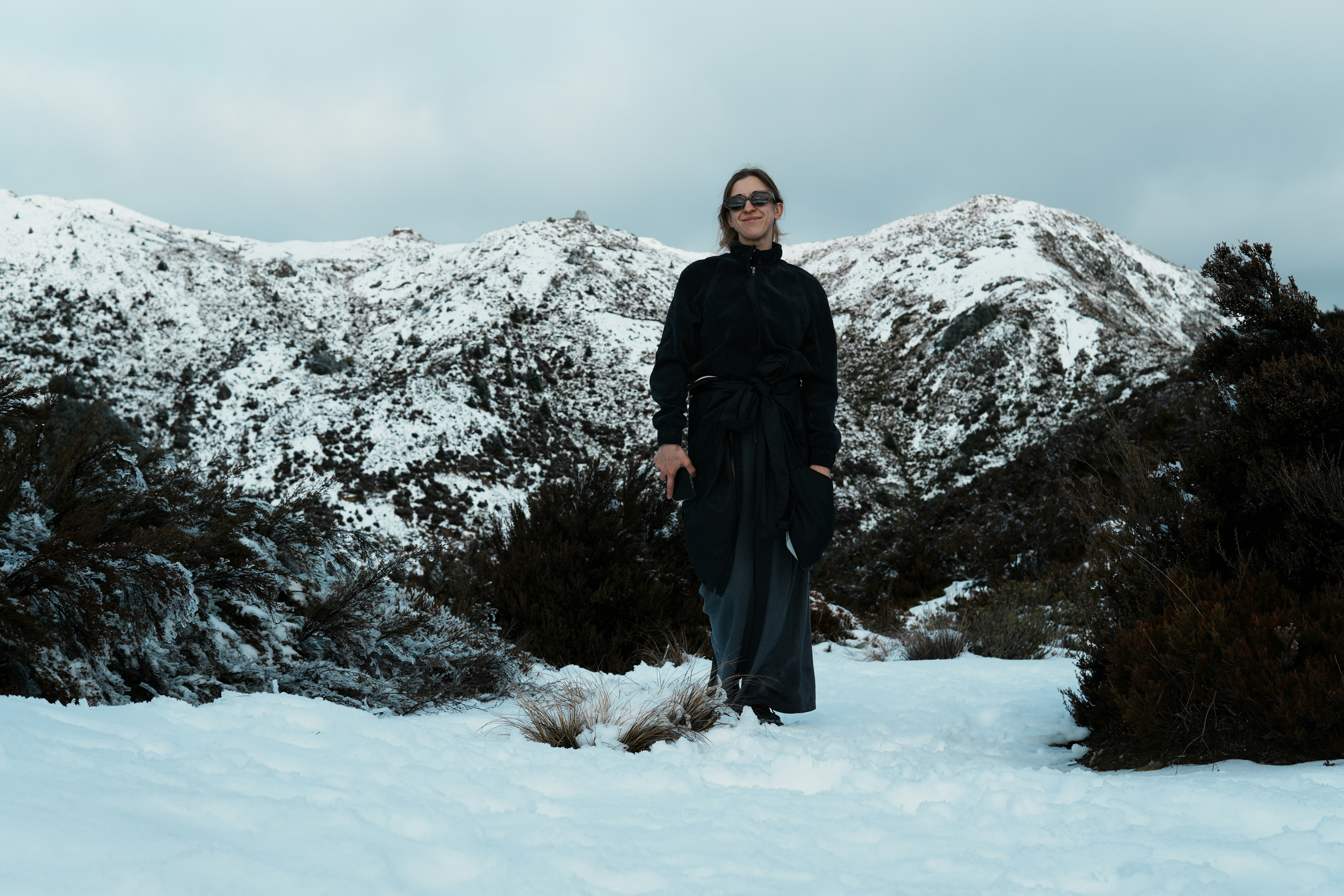 A person in a black jacket and skirt on a snowy mountain path