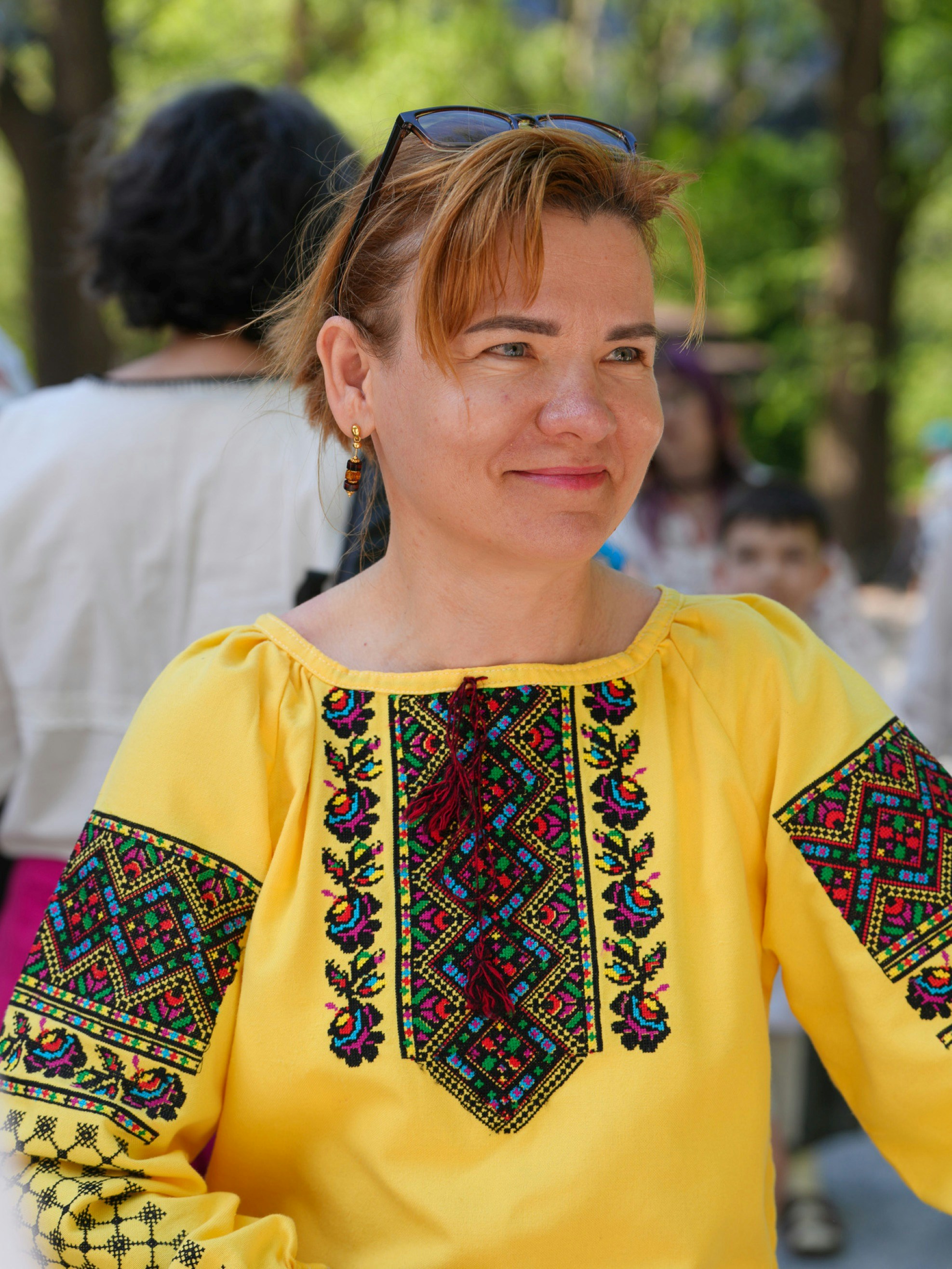 A woman wearing a yellow embroidered vyshyvanka shirt with colorful geometric patterns