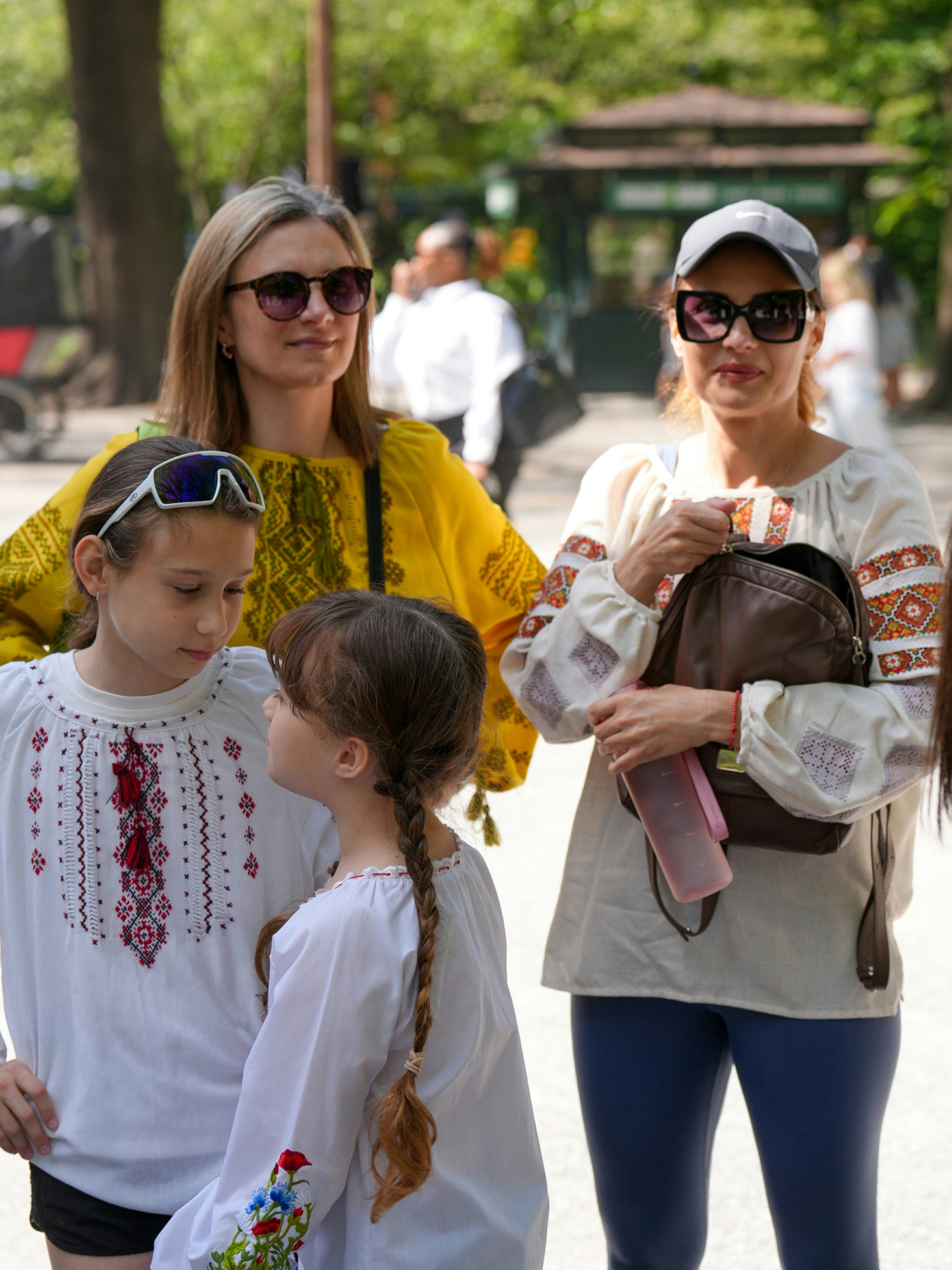 Two adults and two children in embroidered shirts standing together in a park