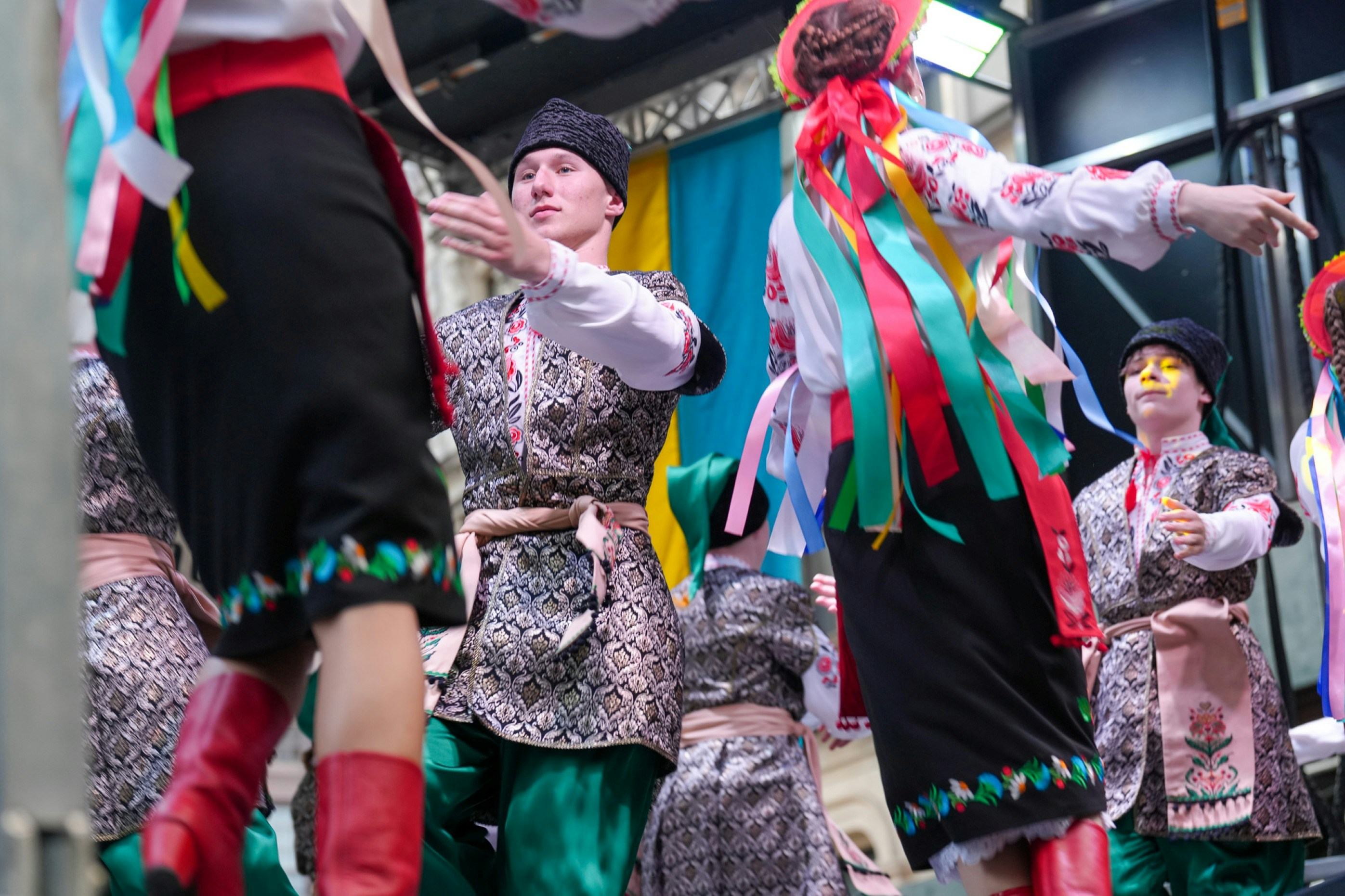 Dancers in traditional Ukrainian folk costumes performing on a stage with colorful ribbons