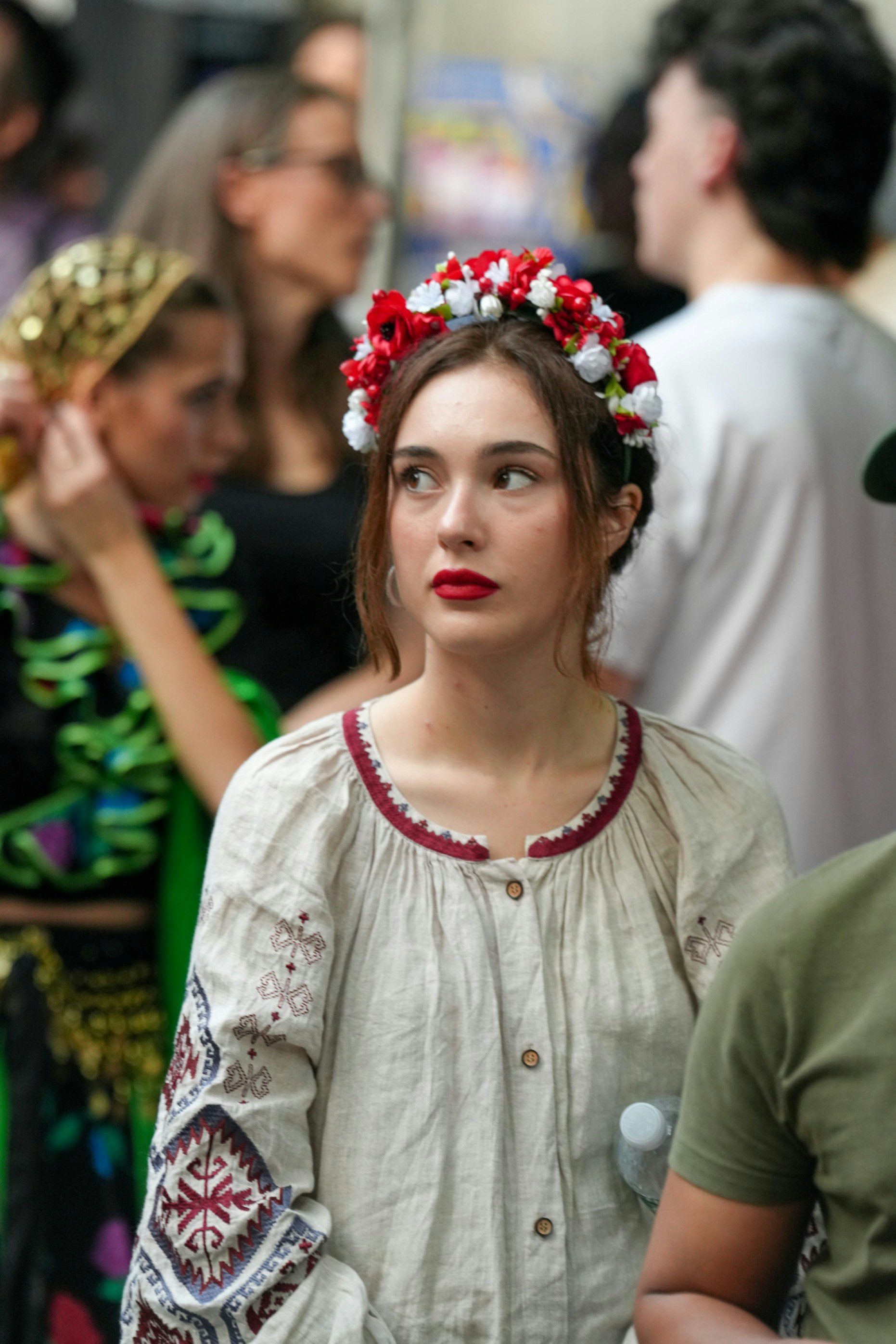 A woman wearing a floral crown and embroidered linen blouse in a crowd